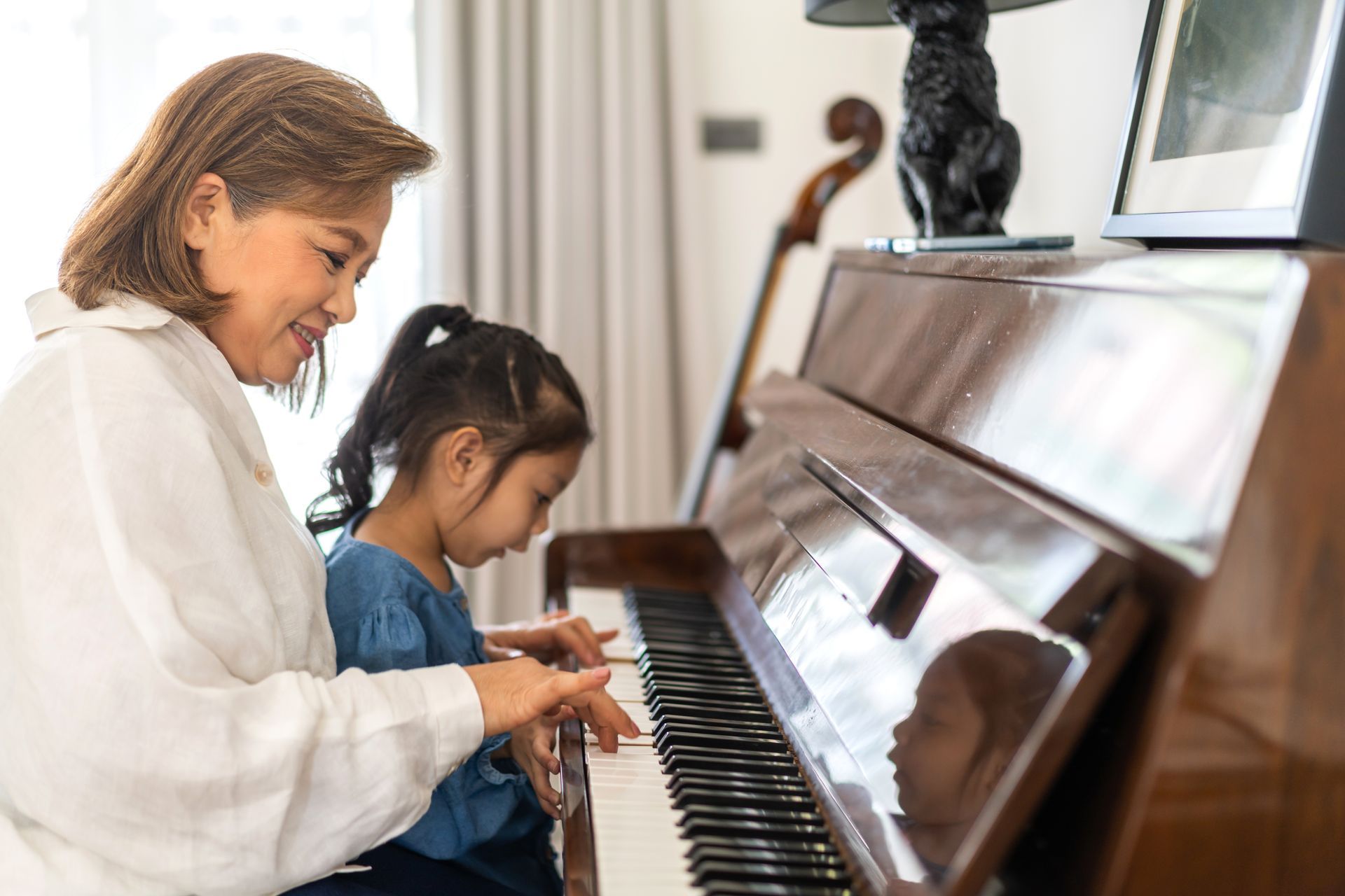 a woman and a little girl are playing a piano together .