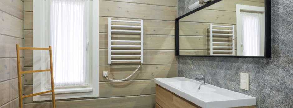 A bathroom with a sink , mirror and towel rack.