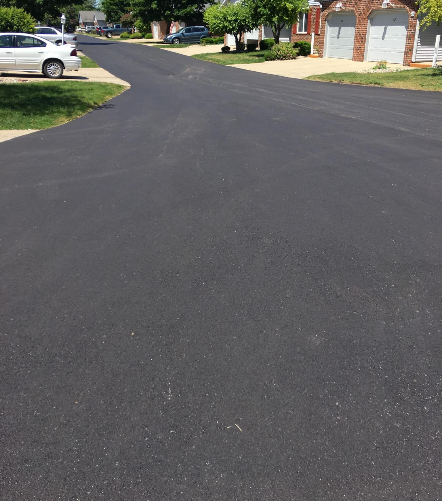 Newly paved asphalt road in residential neighborhood on a sunny day.