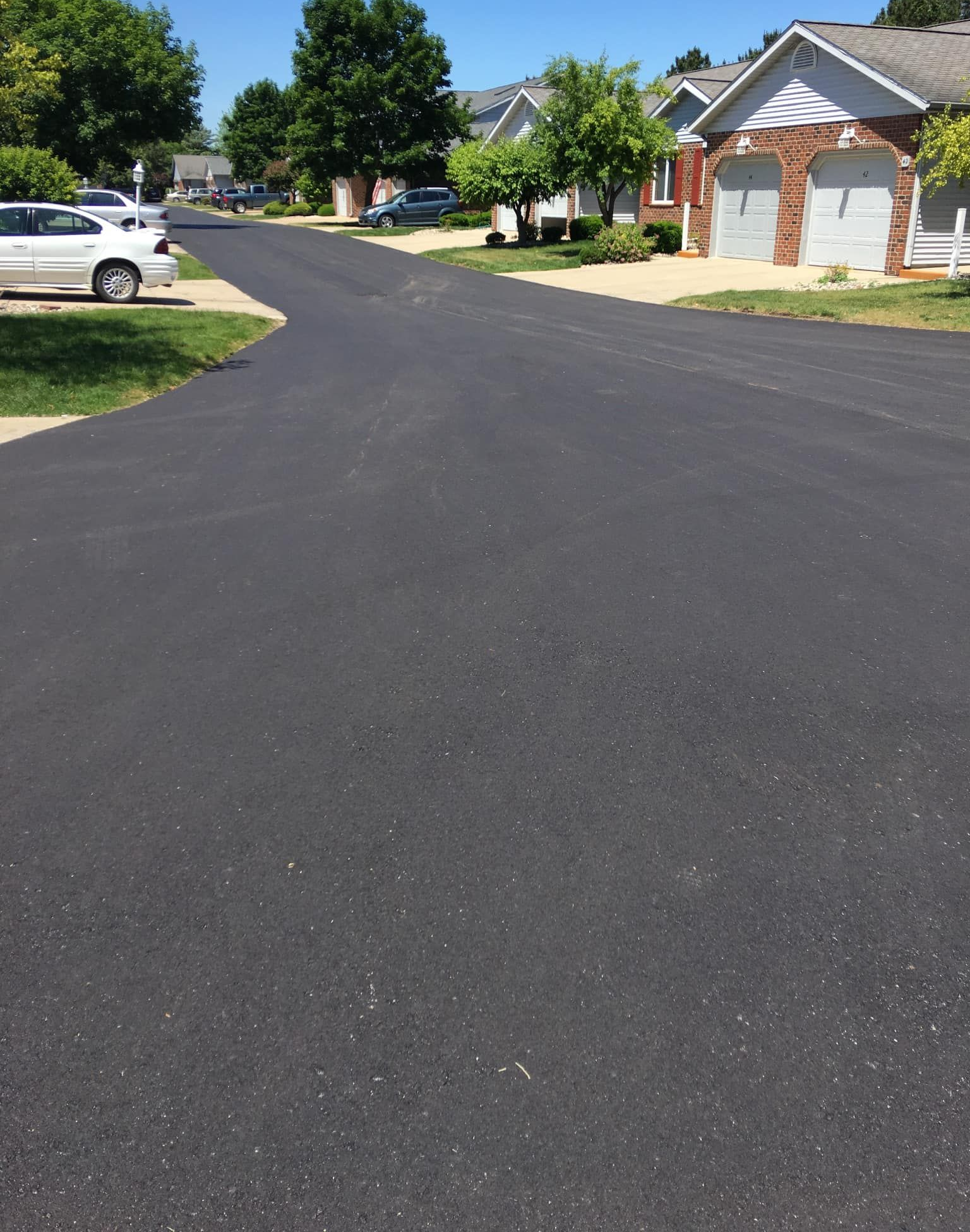 Newly paved asphalt road in residential neighborhood on a sunny day.