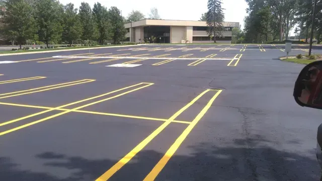 Newly painted asphalt parking lot with yellow parking space lines. A building is visible in the background.
