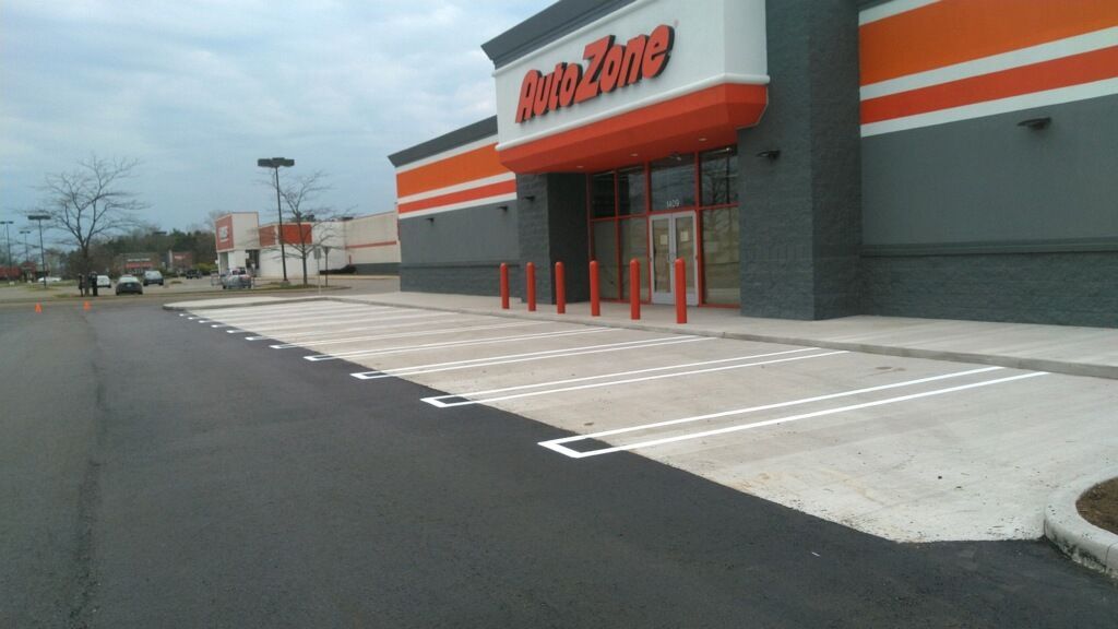 A building with a brick facade and new asphalt parking lot with yellow and blue markings.