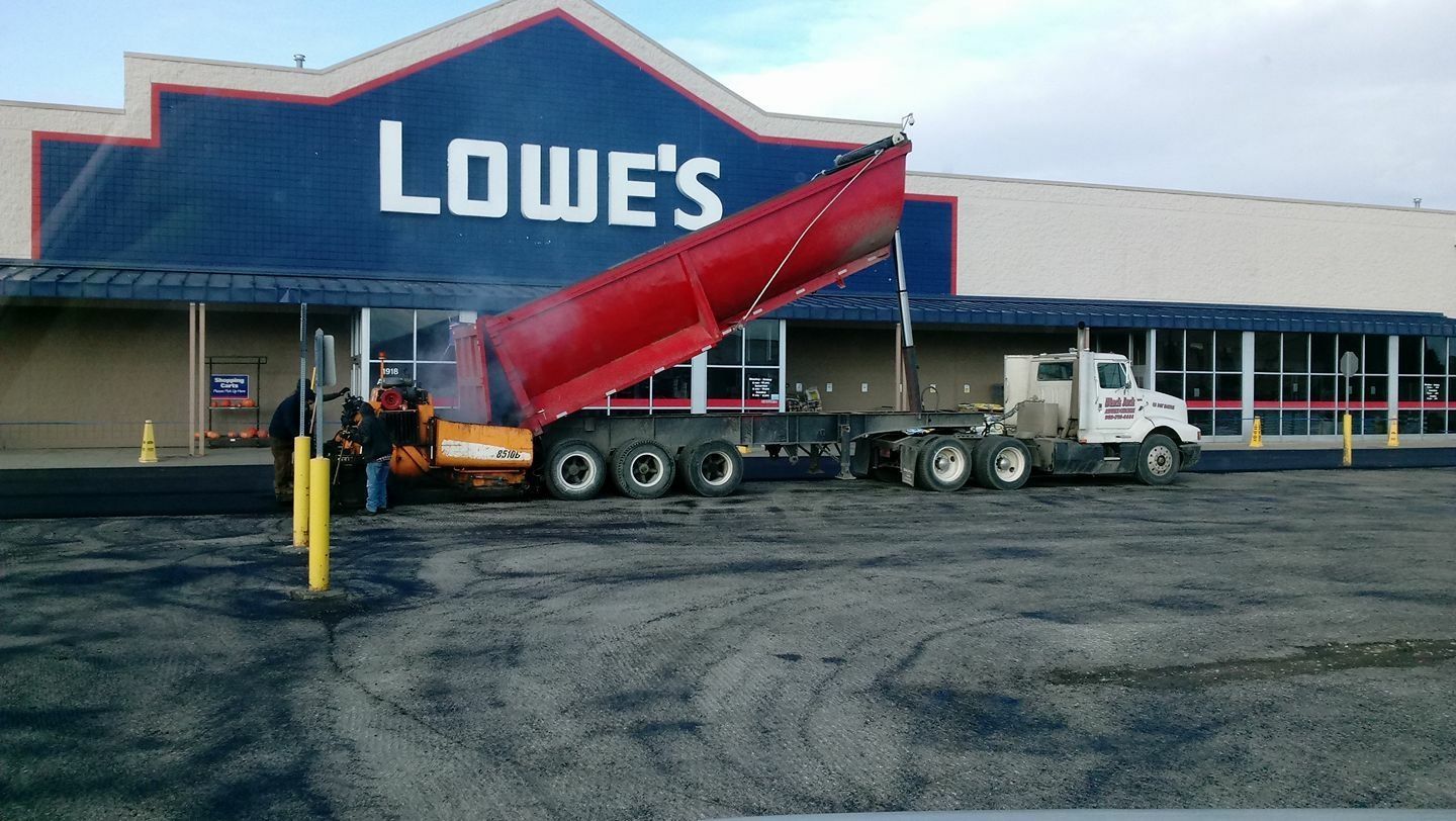 Asphalt paving at night. A machine lays black asphalt under bright streetlights. 
