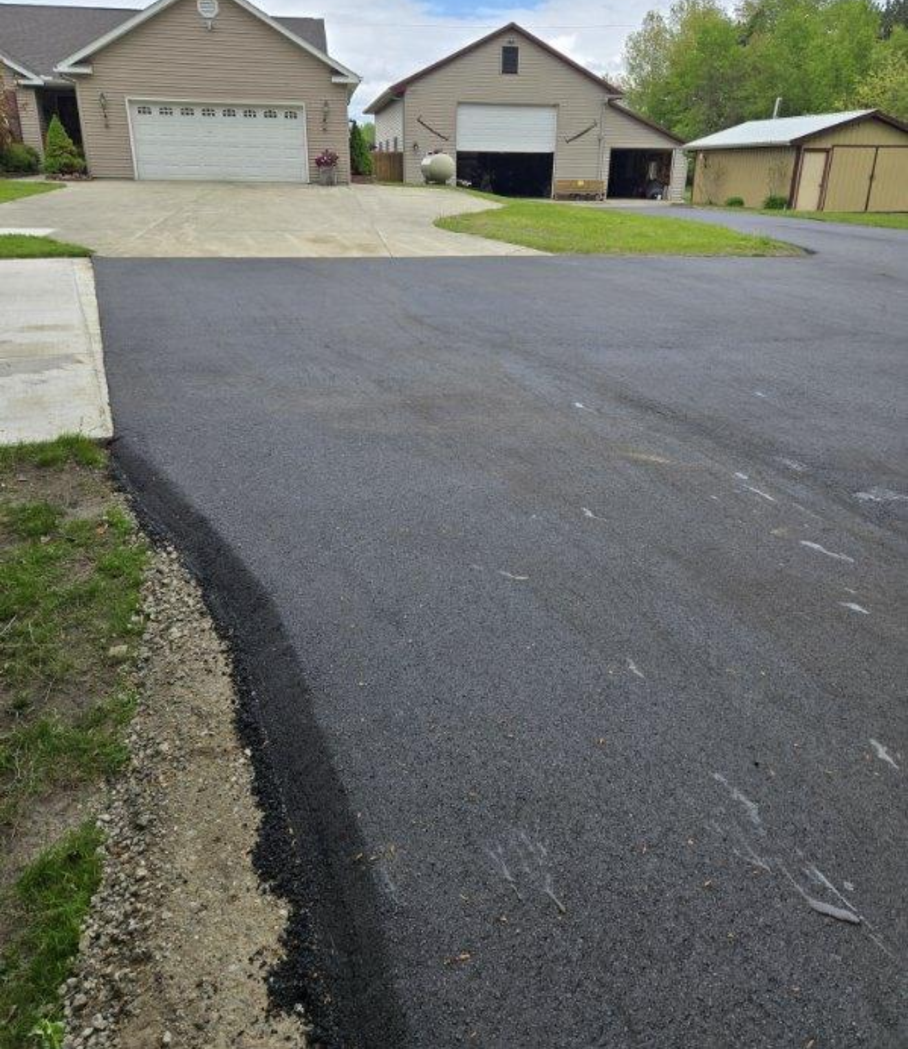 Asphalt path through green park, leading to a field.