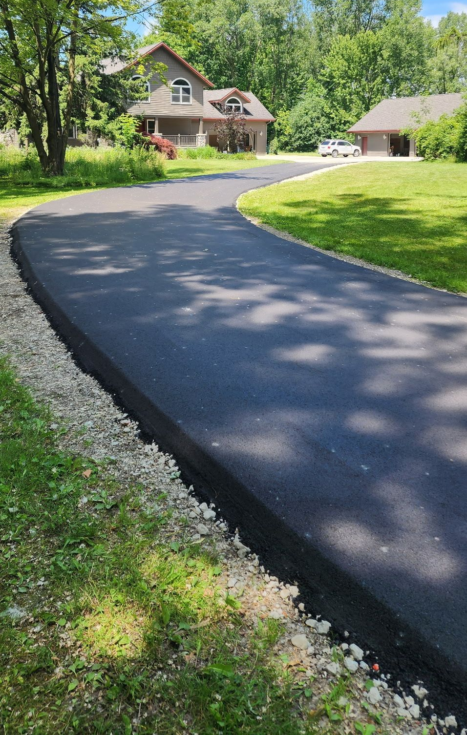 Asphalt paving crew at work, truck dumping asphalt onto paver in a cemetery, sunny day.
