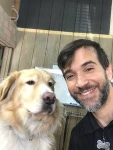 A man with a beard is taking a selfie with his dog.