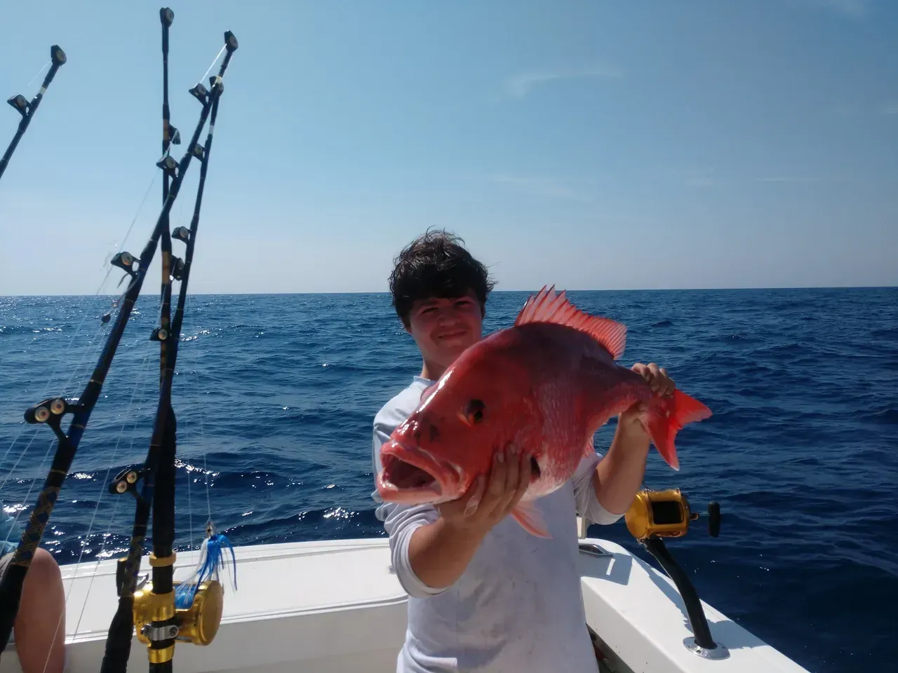 A man is holding a large red fish on a boat
