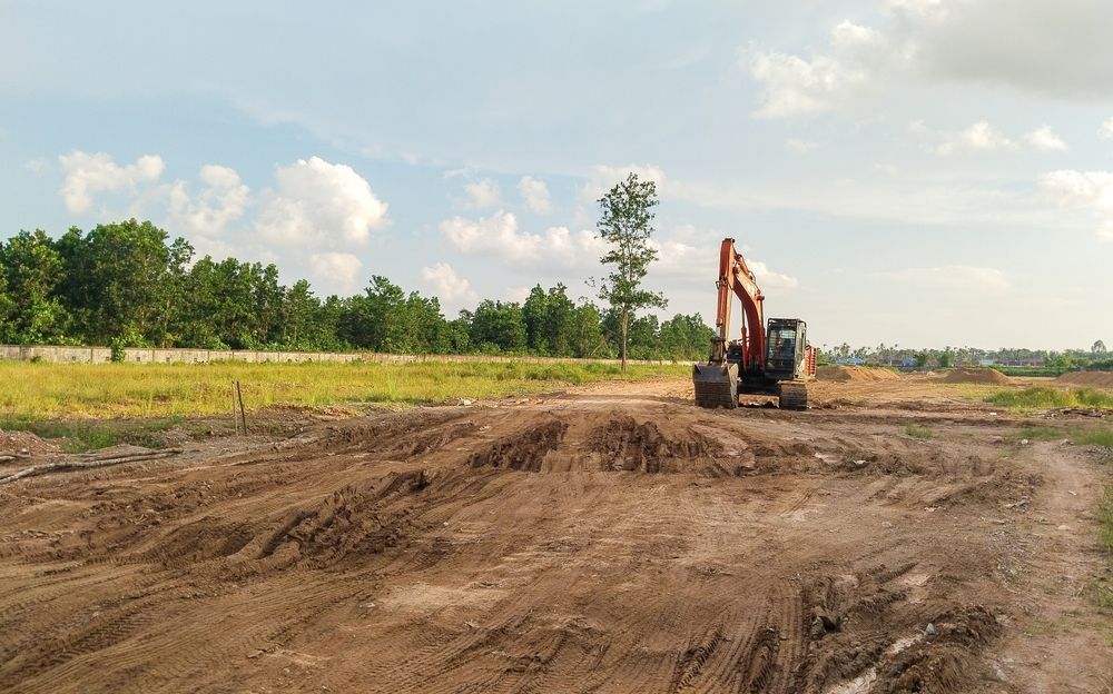 An excavator is digging a hole in a dirt field.