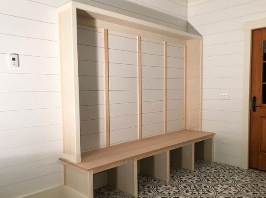 A wooden bench is sitting in a hallway next to a door.