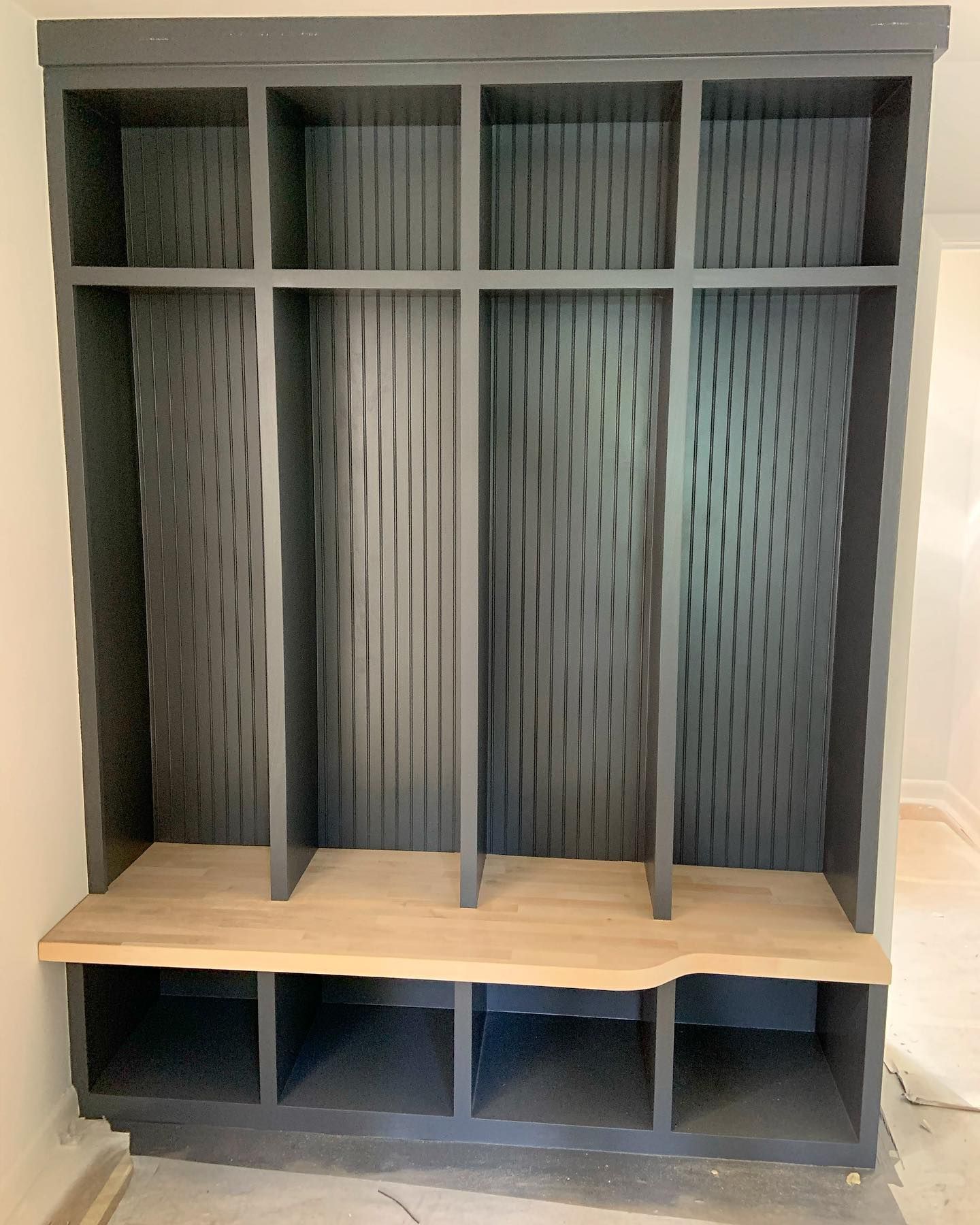 A gray locker with a wooden bench underneath it