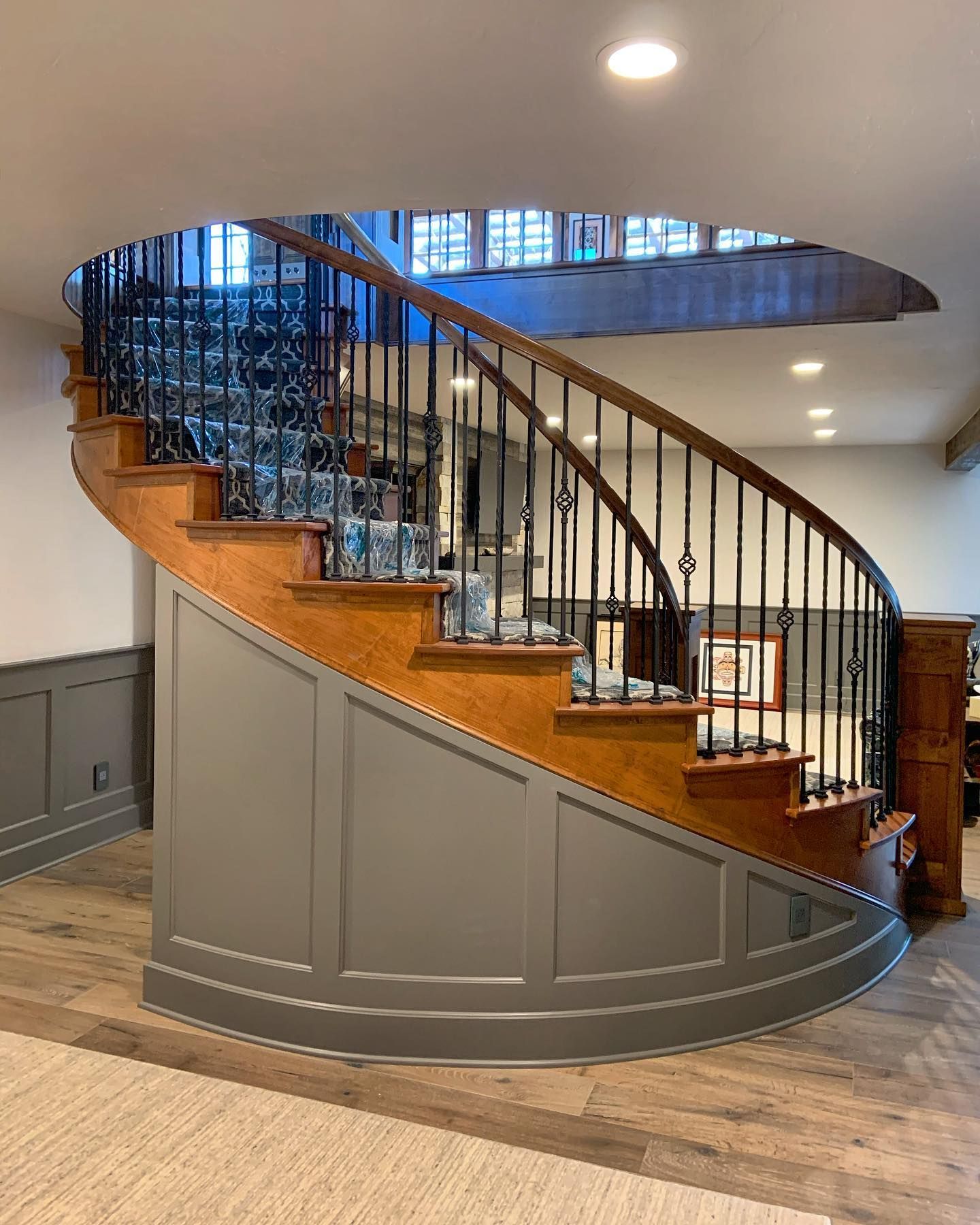 A wooden spiral staircase with a metal railing in a house.