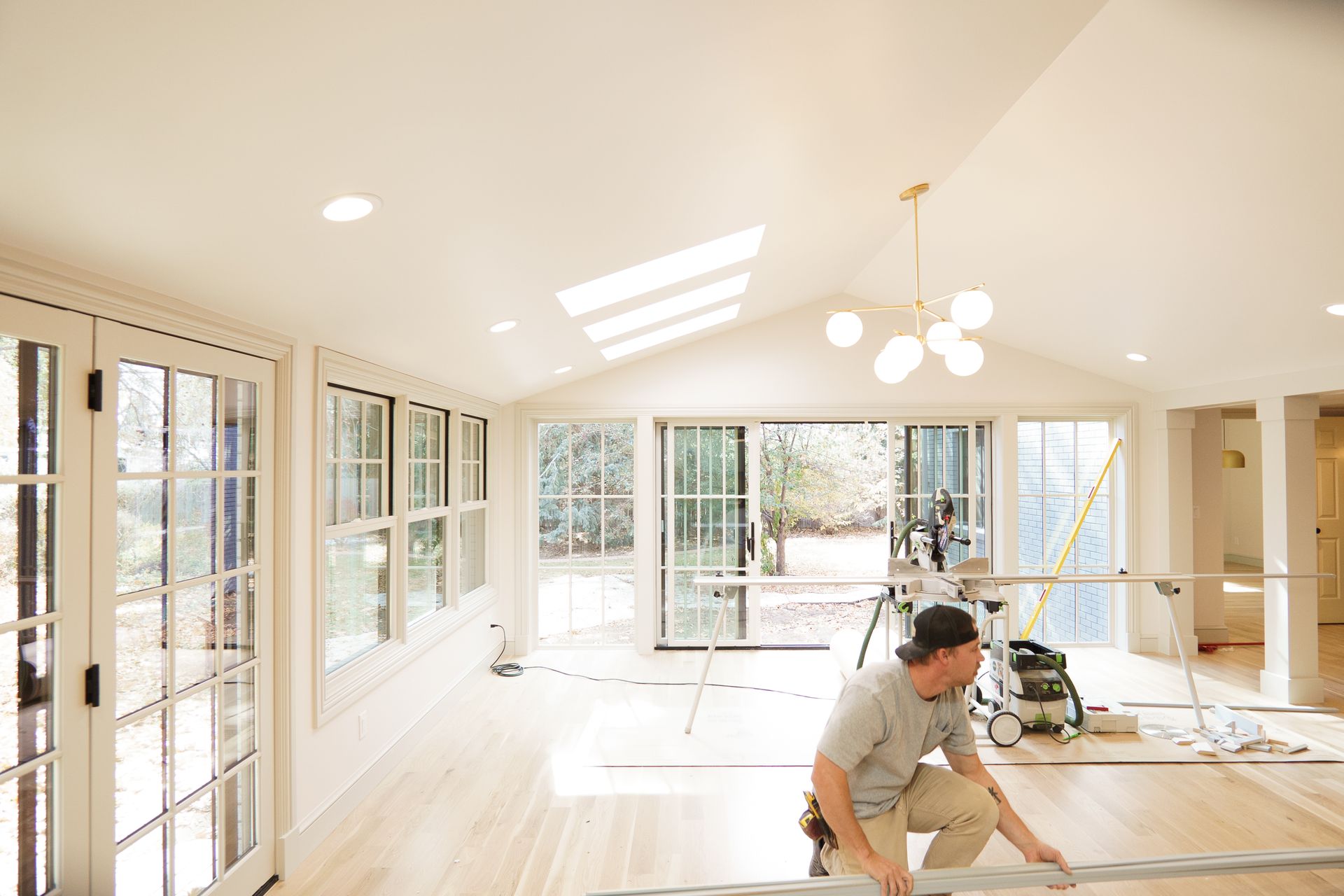 A man is measuring a piece of wood in a large room.