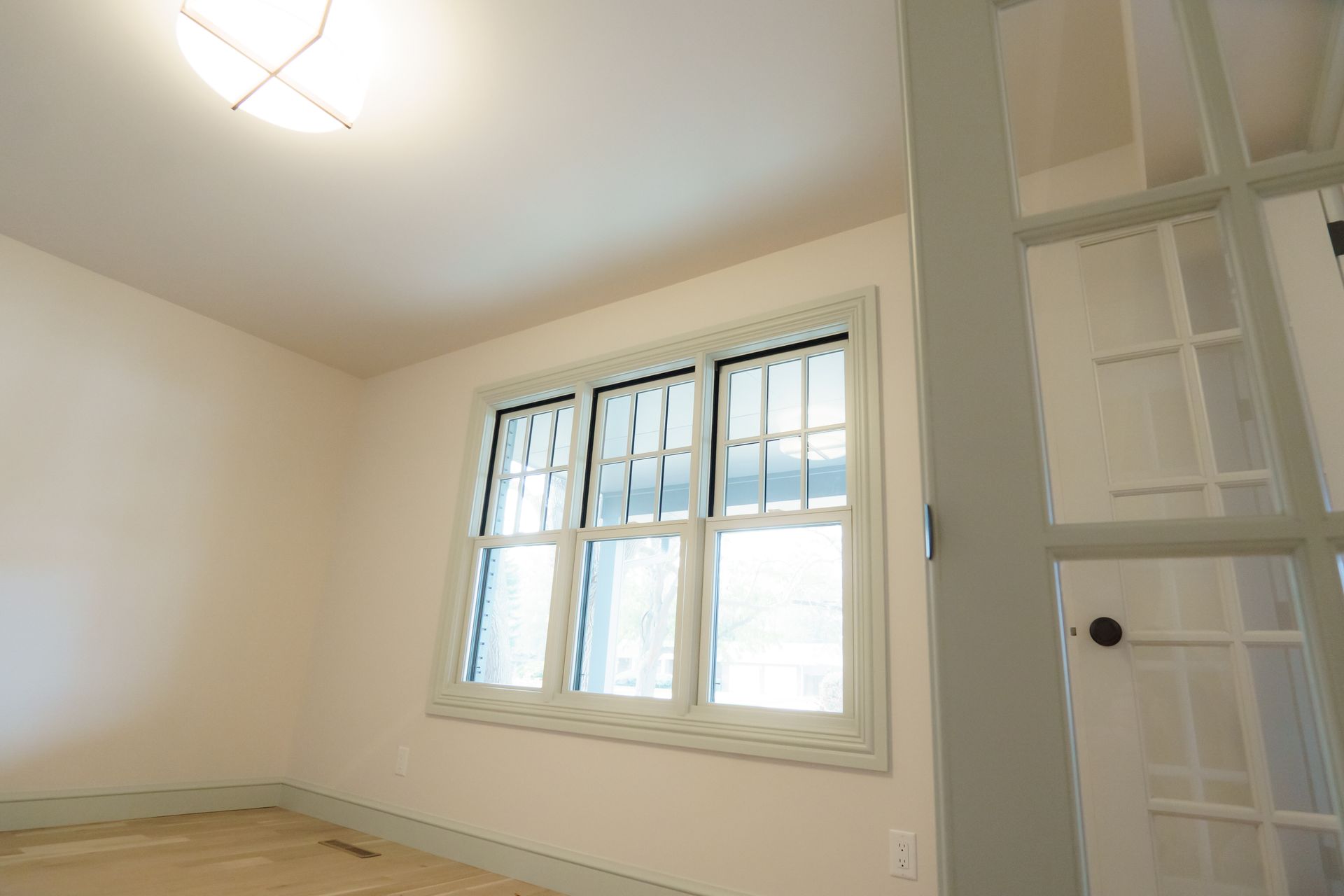 An empty room with three windows and a door.