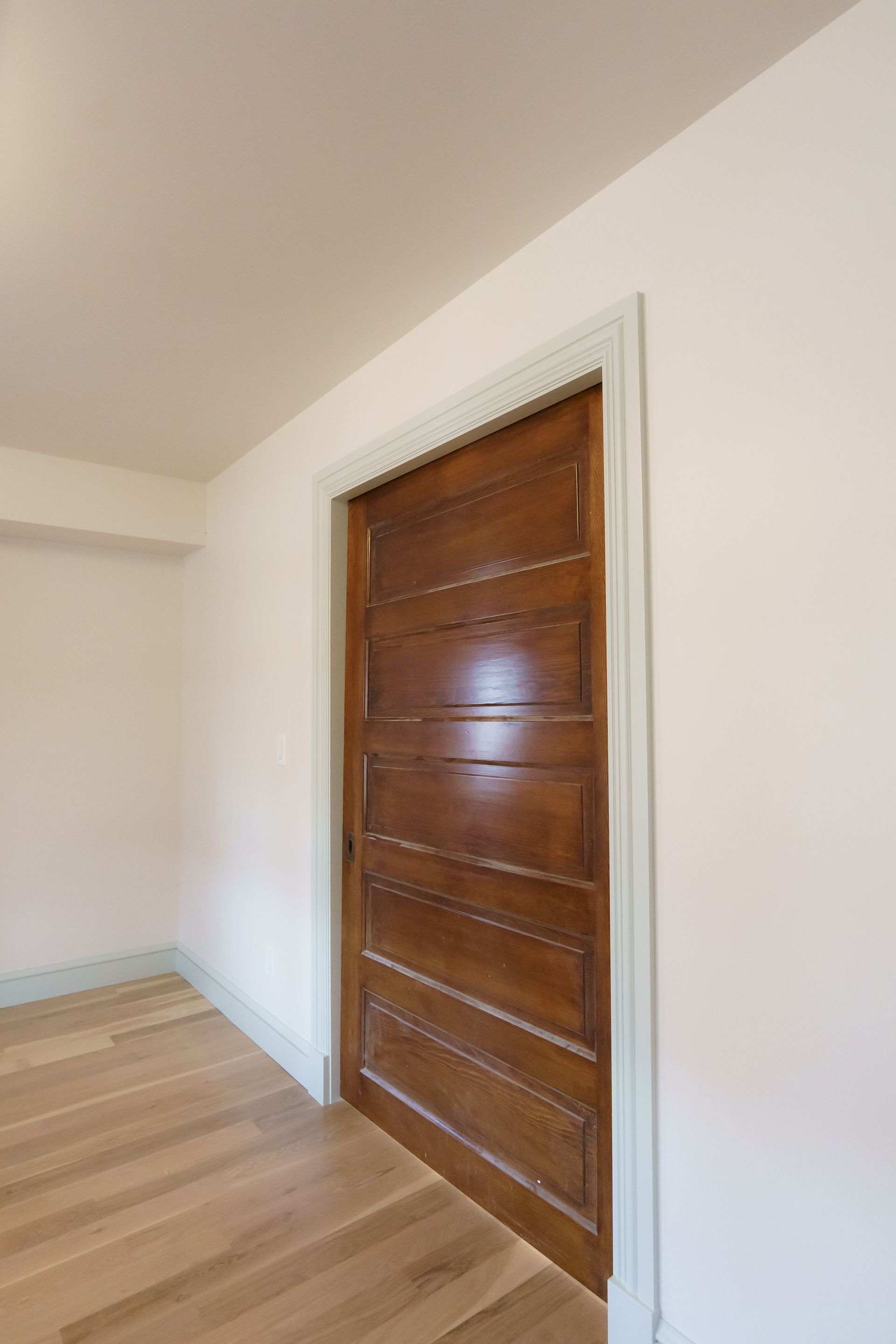 An empty room with a wooden door and white walls.