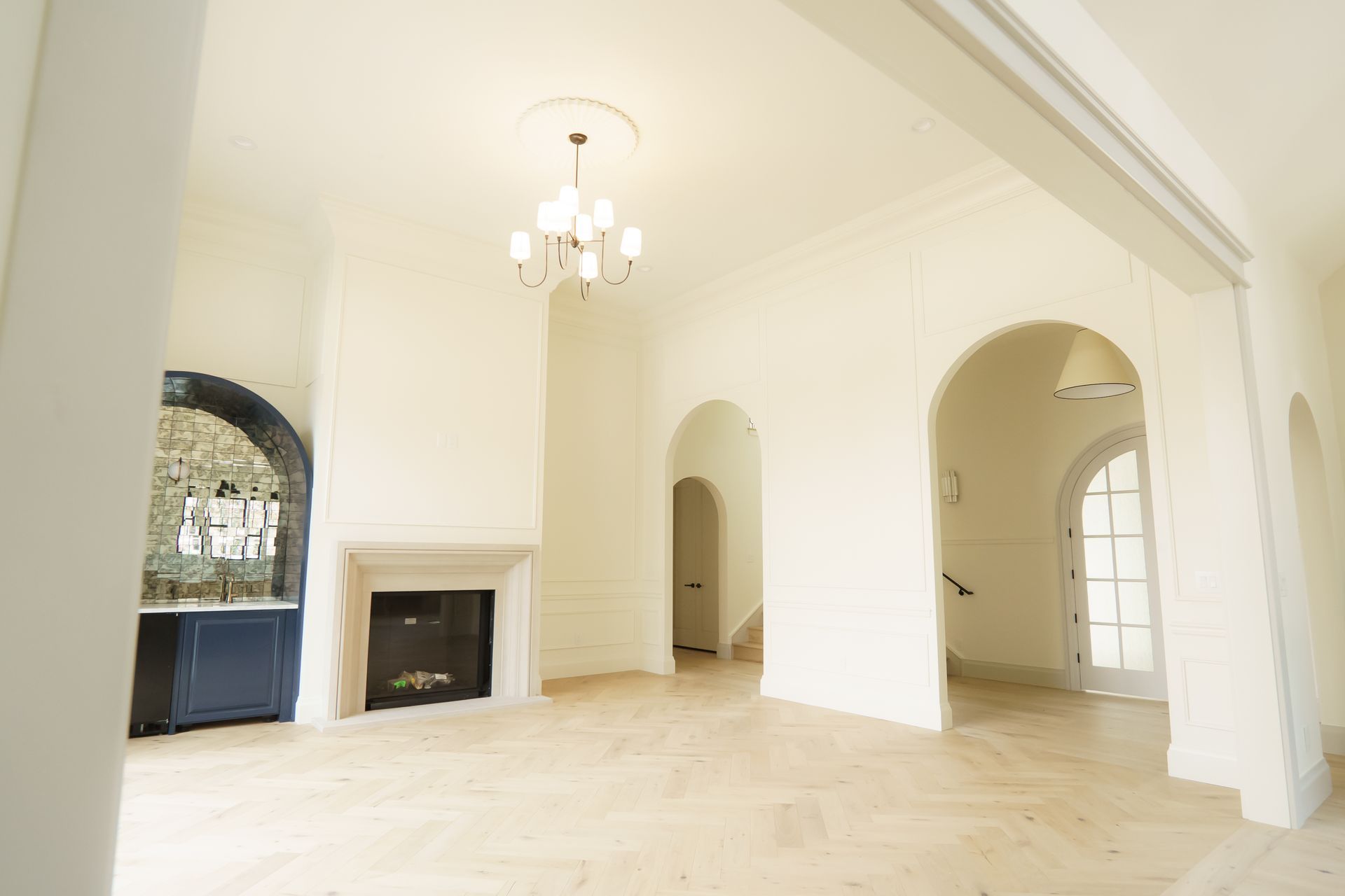 An empty living room with arches and a fireplace