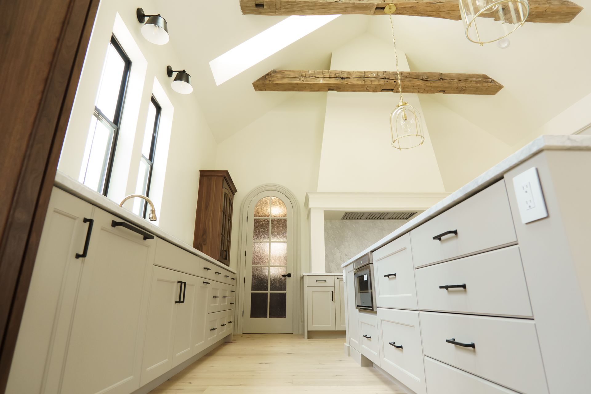 A kitchen with a lot of cabinets and drawers and a ceiling with wooden beams.