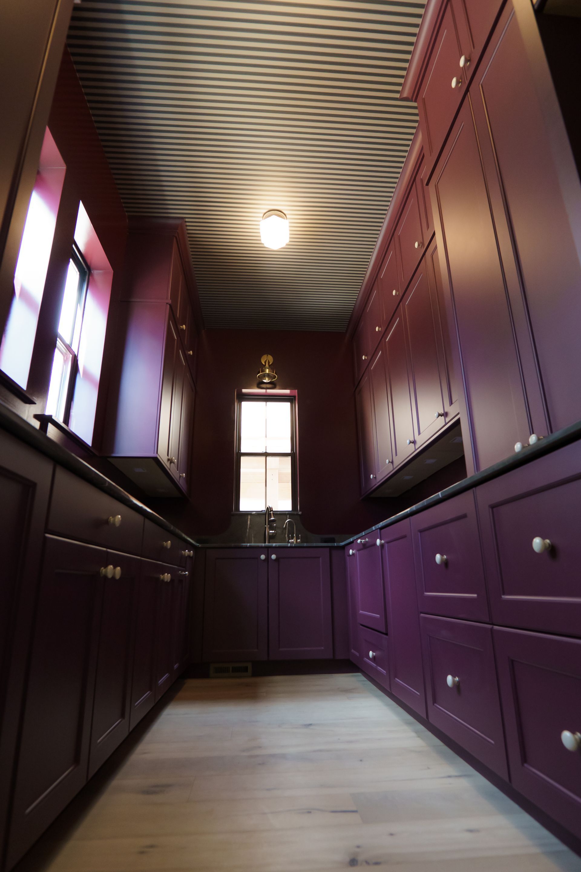 A kitchen with purple cabinets and a striped ceiling
