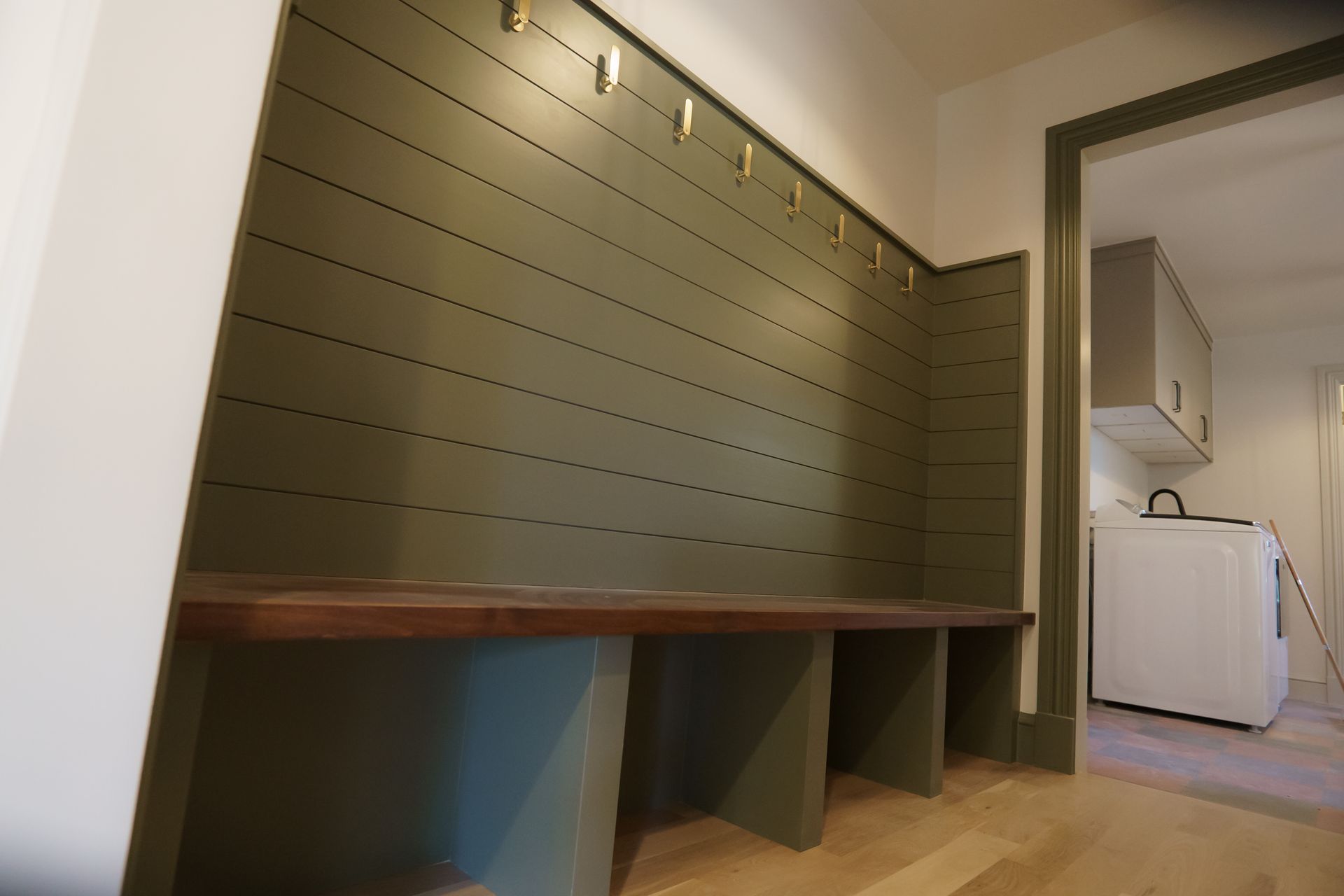 A laundry room with a bench and hooks on the wall