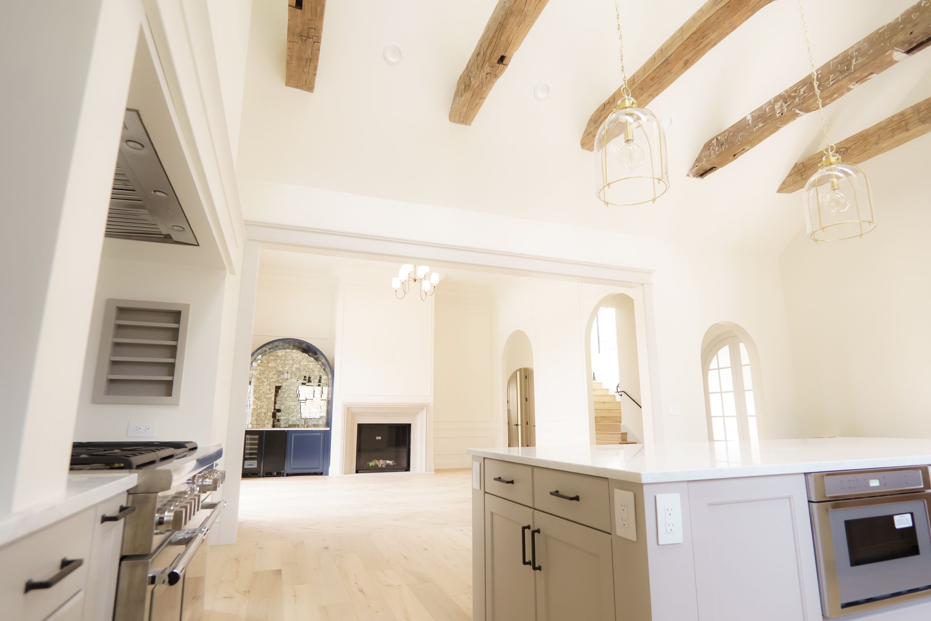 A kitchen with a large island in the middle and wooden beams on the ceiling.