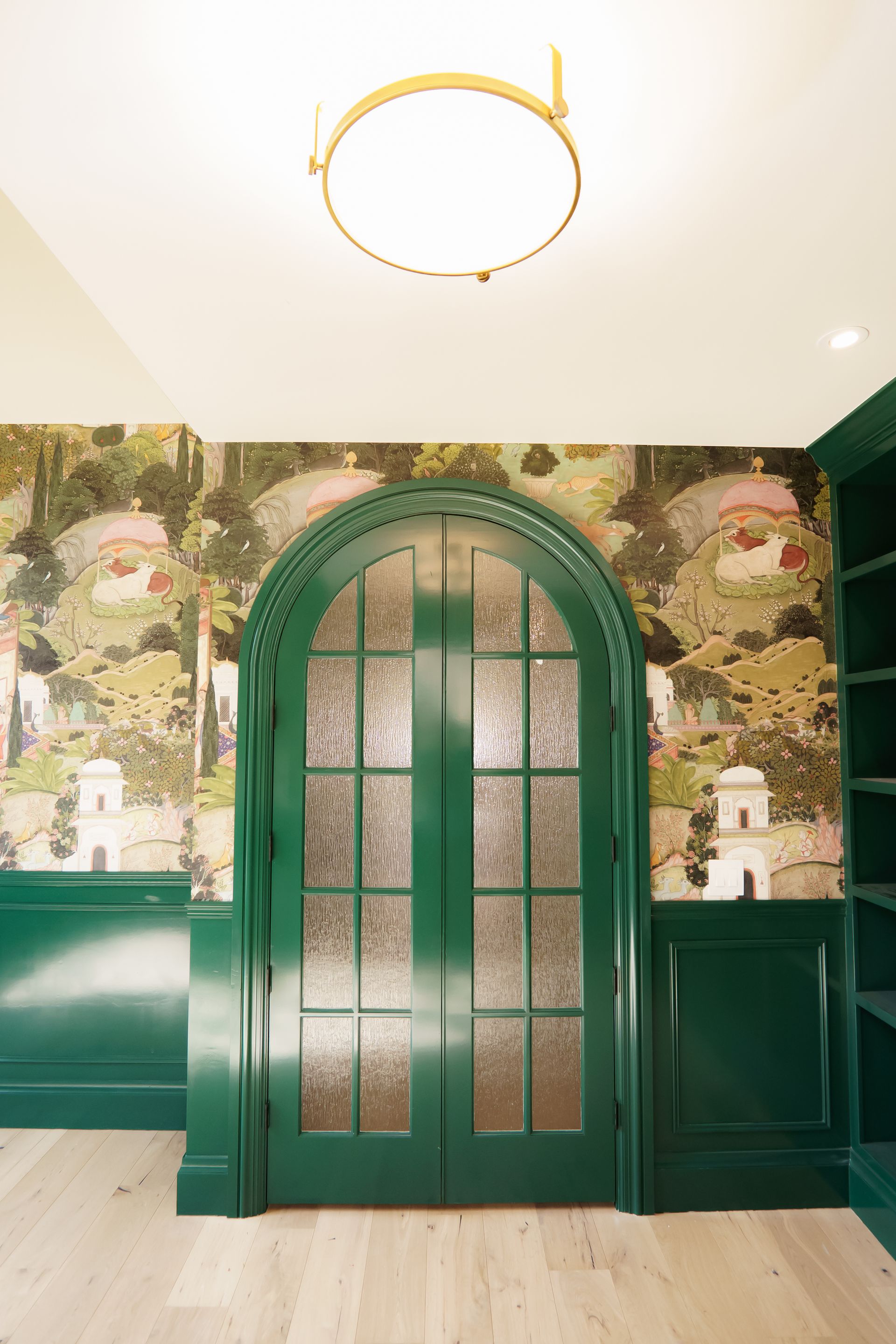 A green door with a stained glass window in a room with a ceiling light.