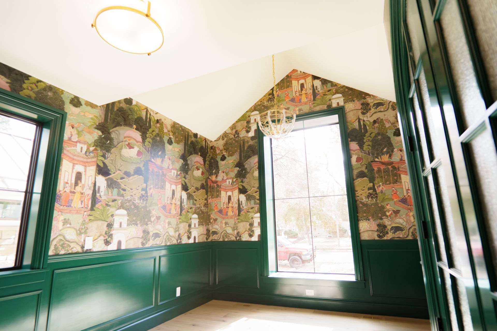 A room with green walls and a chandelier hanging from the ceiling.