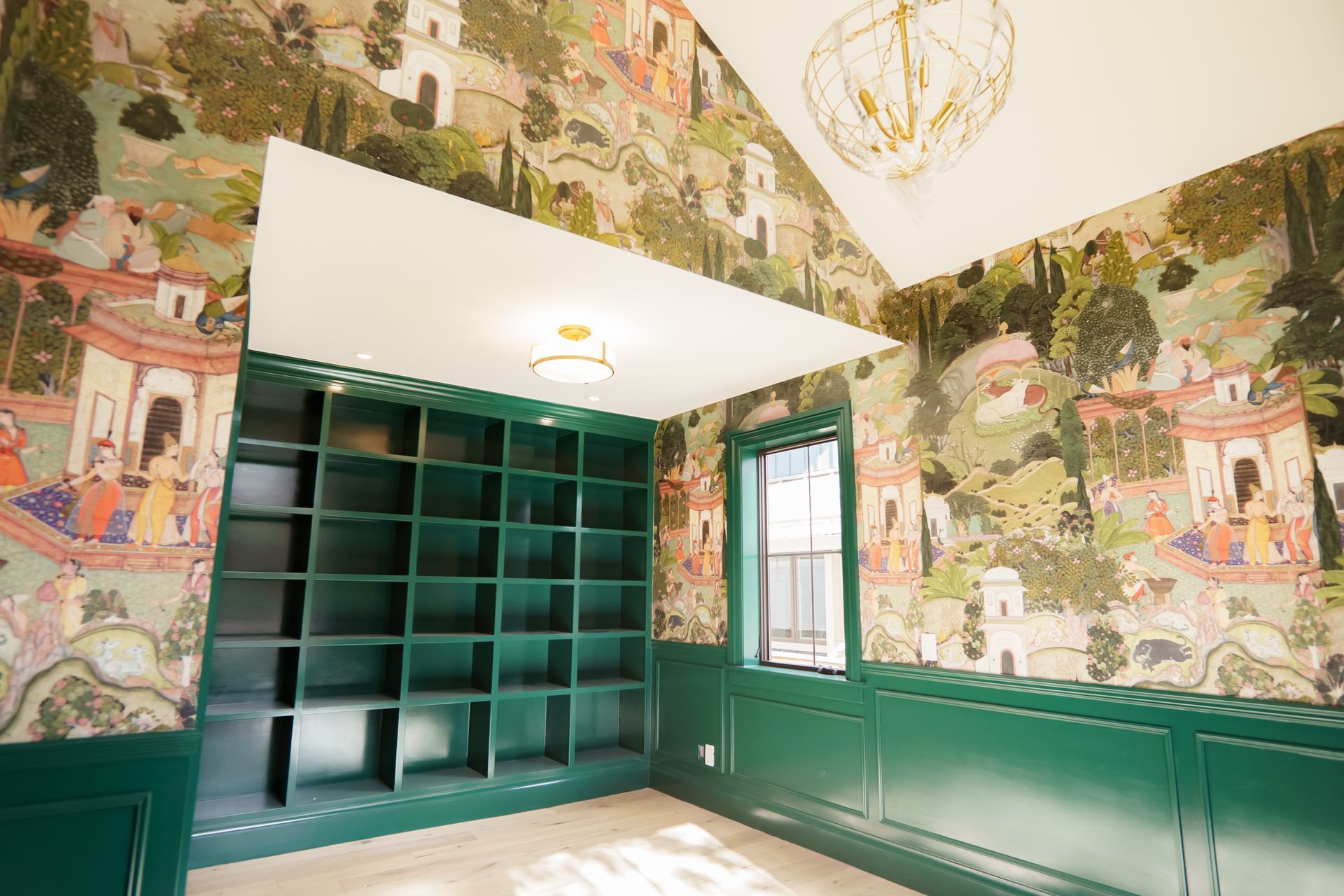 A room with green walls and shelves and a chandelier.