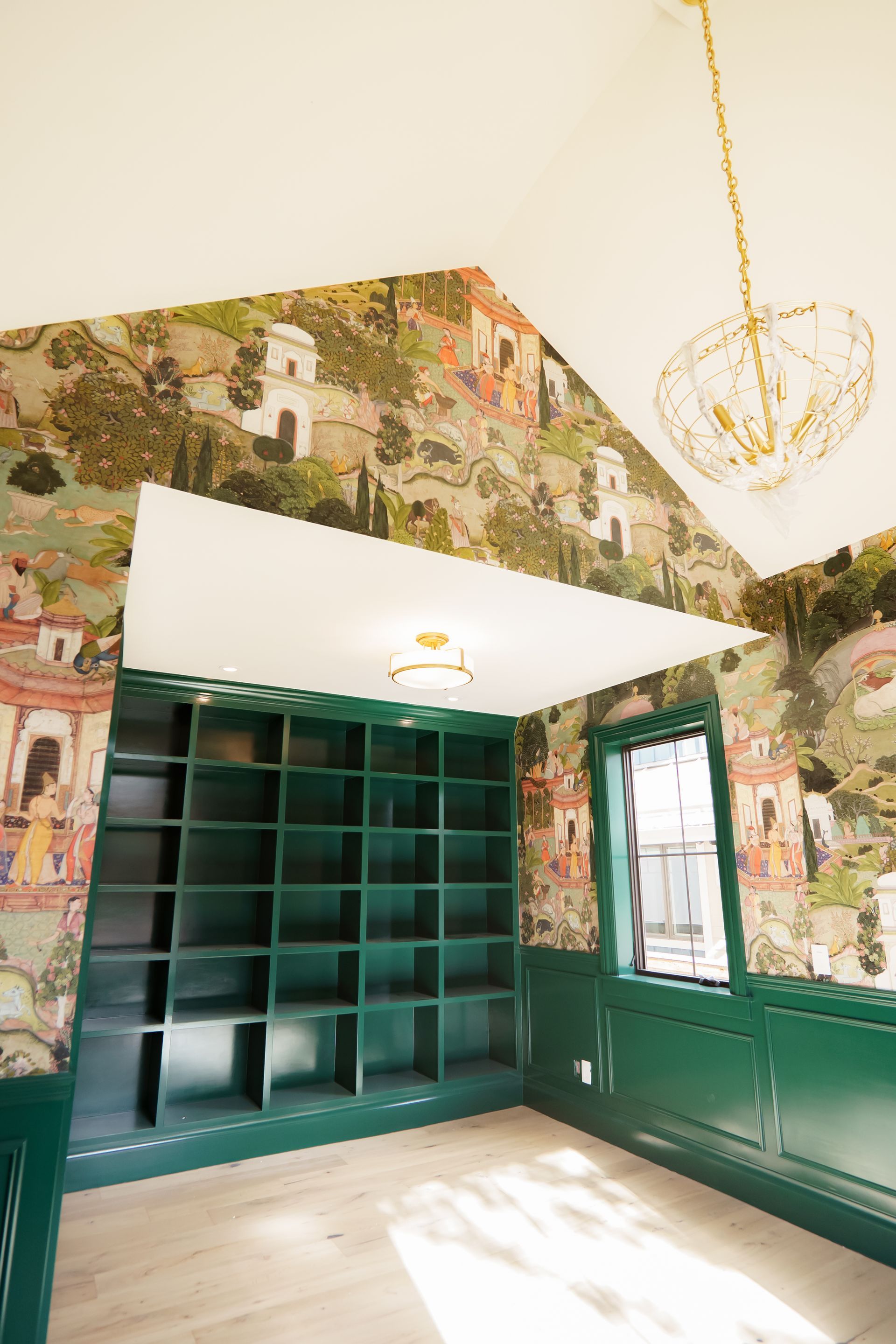 A room with green shelves and a chandelier hanging from the ceiling.