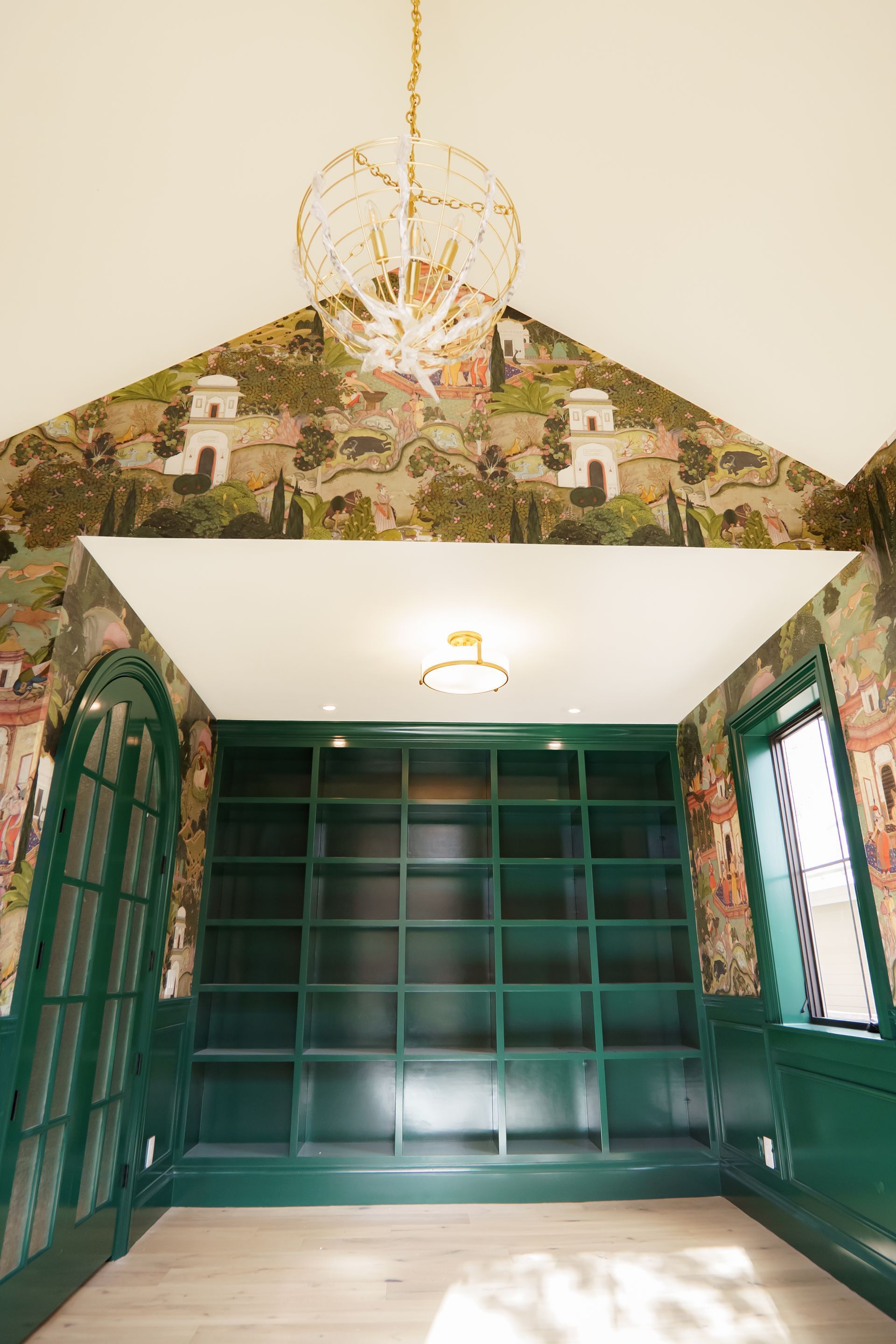 A room with green shelves and a chandelier hanging from the ceiling.