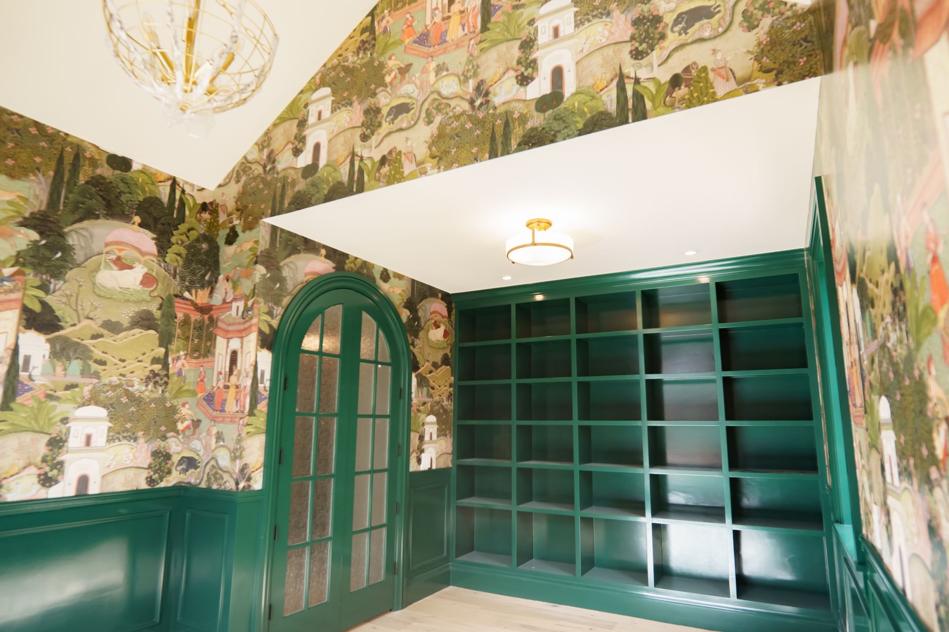 A room with green shelves and a chandelier on the ceiling.