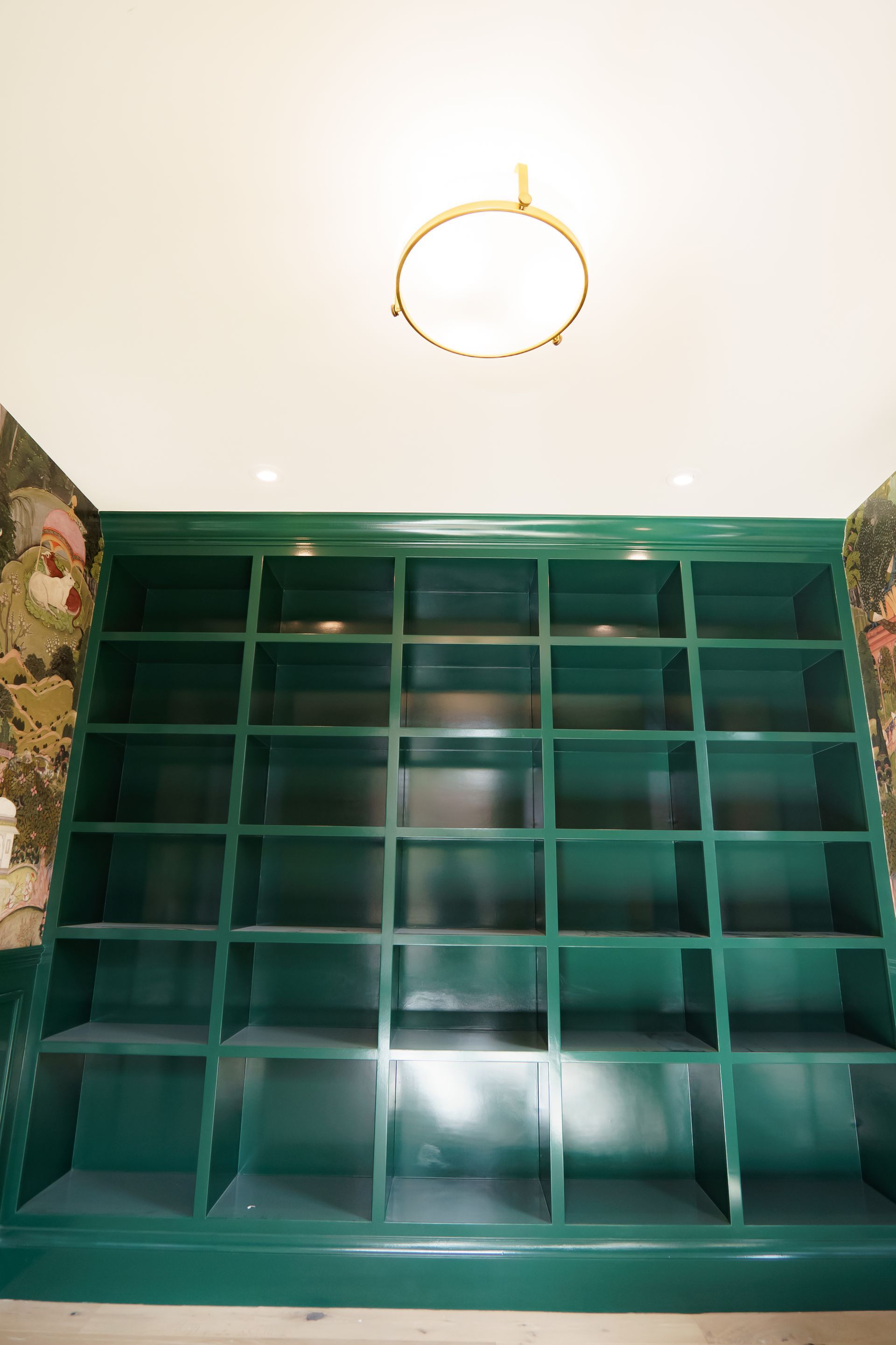 A room with green shelves and a light on the ceiling.