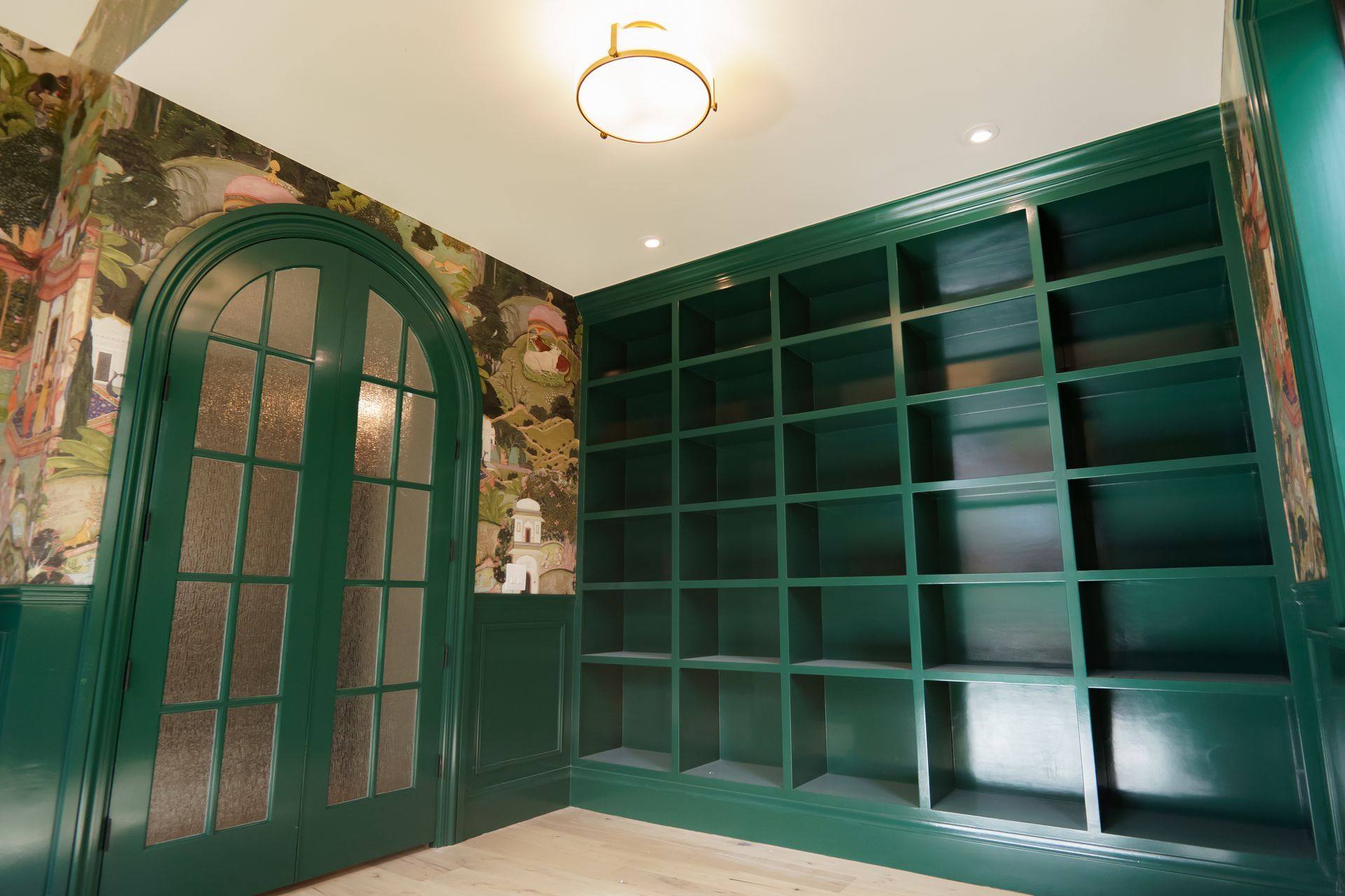 A room with green shelves and doors and a ceiling light.