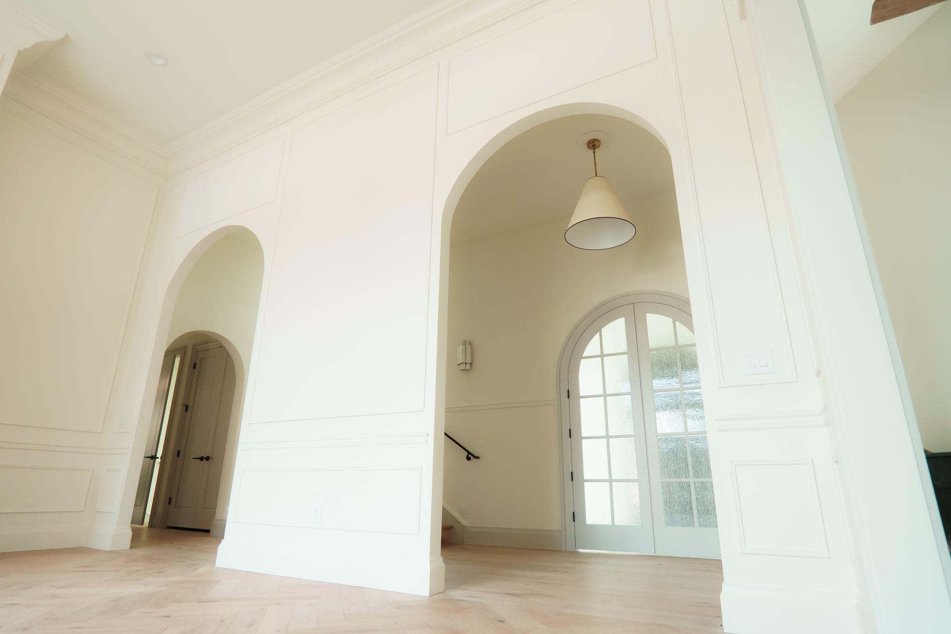 An empty room with arches and a staircase in a house.