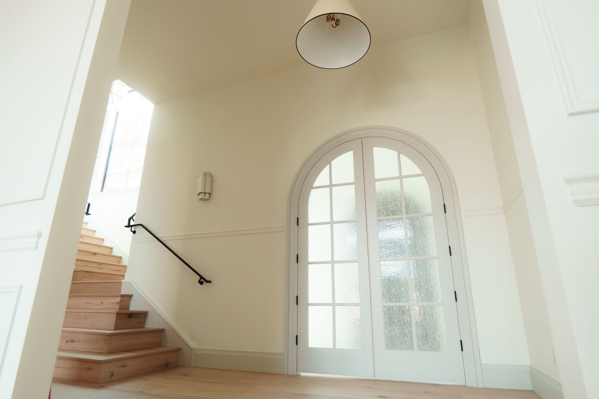 A hallway with arched doors and stairs in a house