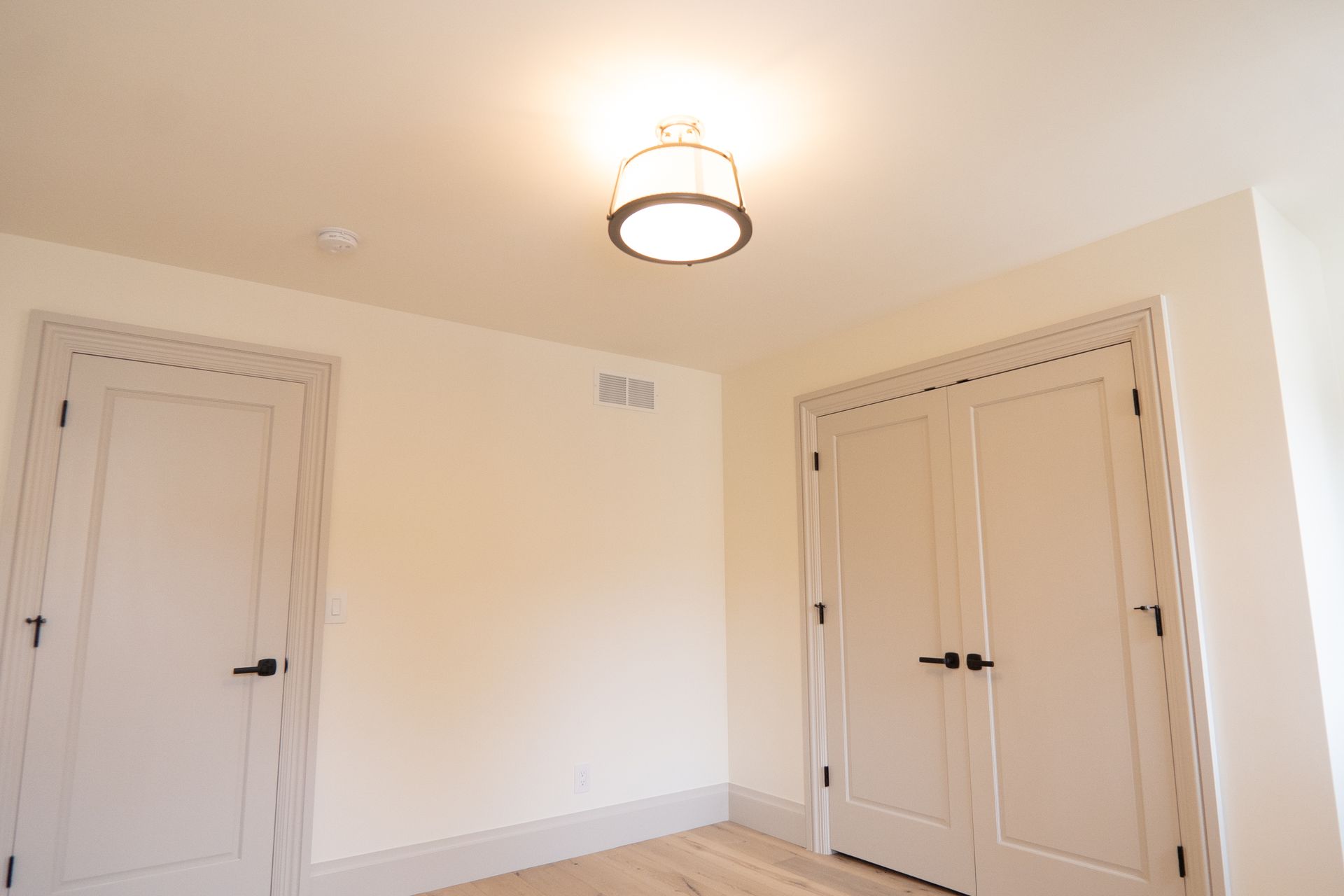 A room with two white doors and a light on the ceiling.