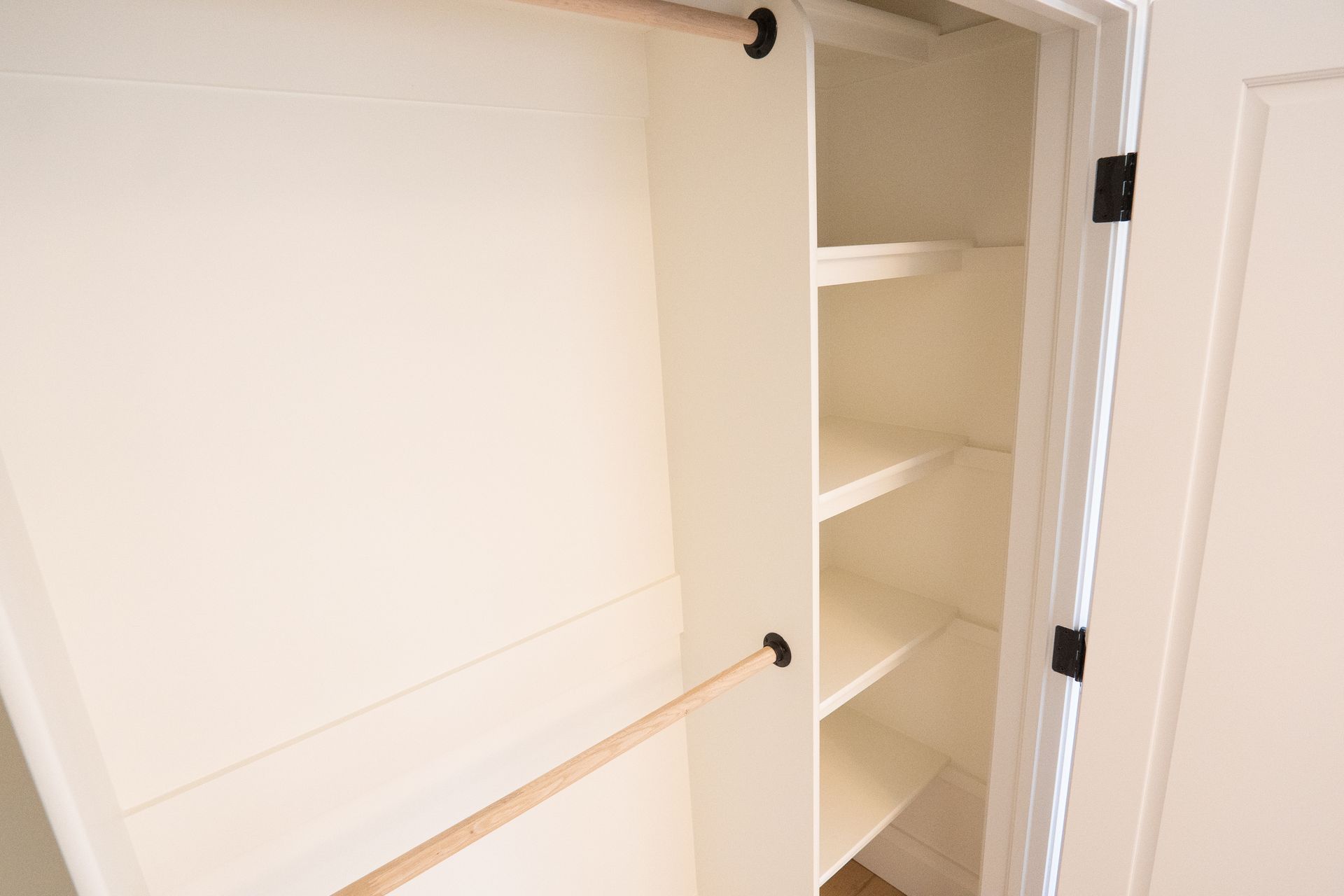 A white closet with shelves and a wooden railing.