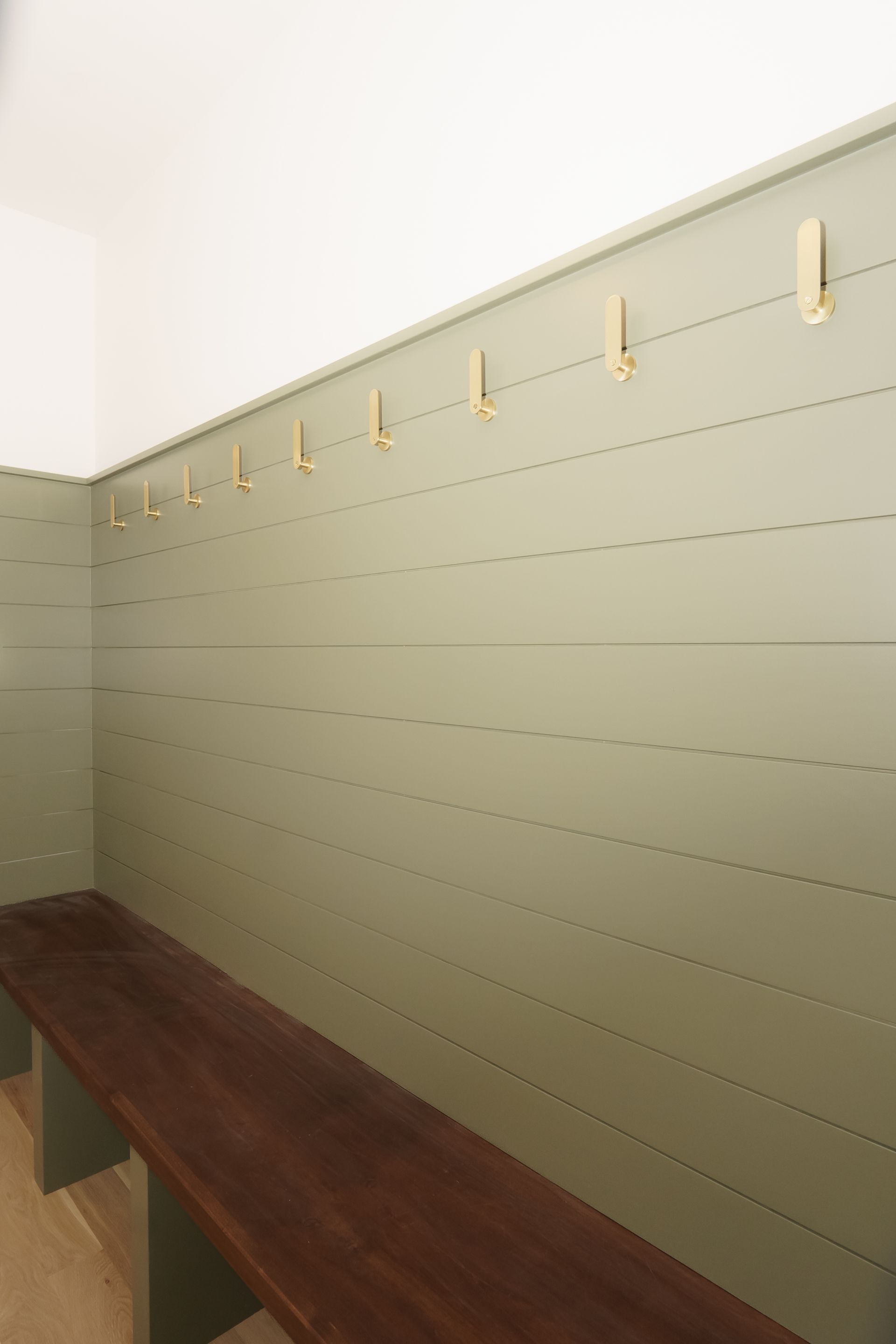 A locker room with a wooden bench and hooks on the wall.
