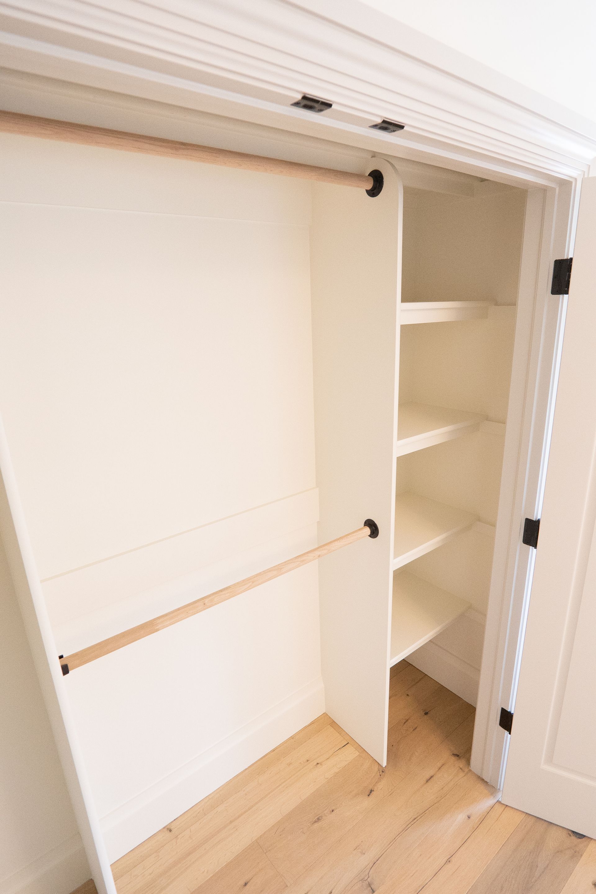 A white closet with shelves and a wooden floor.