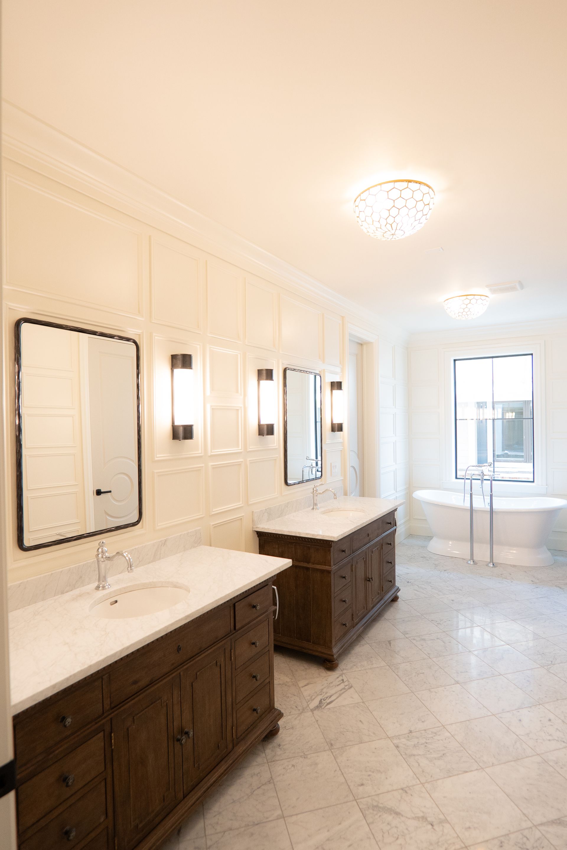 A bathroom with two sinks , two mirrors and a tub.