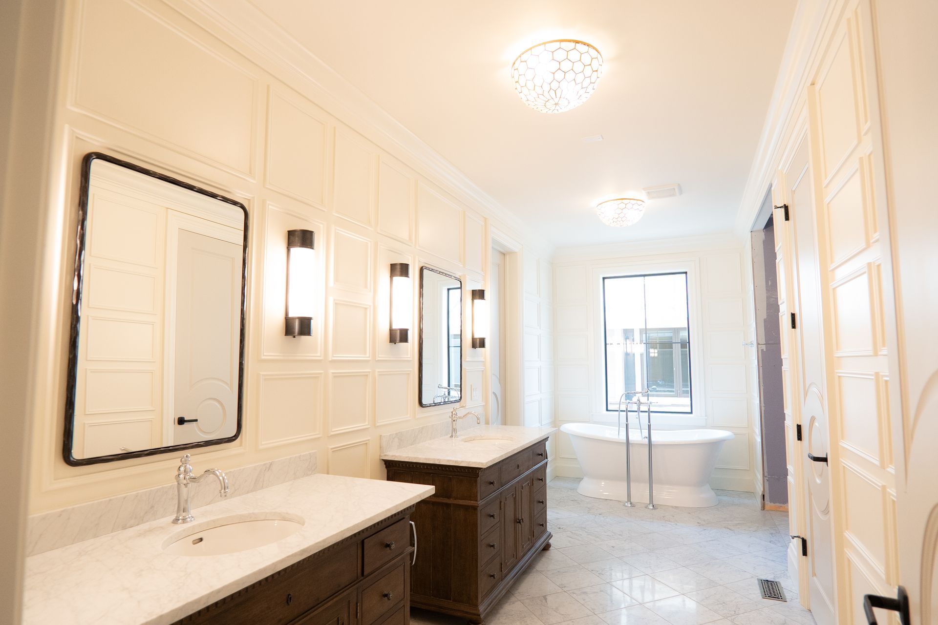 A bathroom with two sinks , two mirrors and a tub.