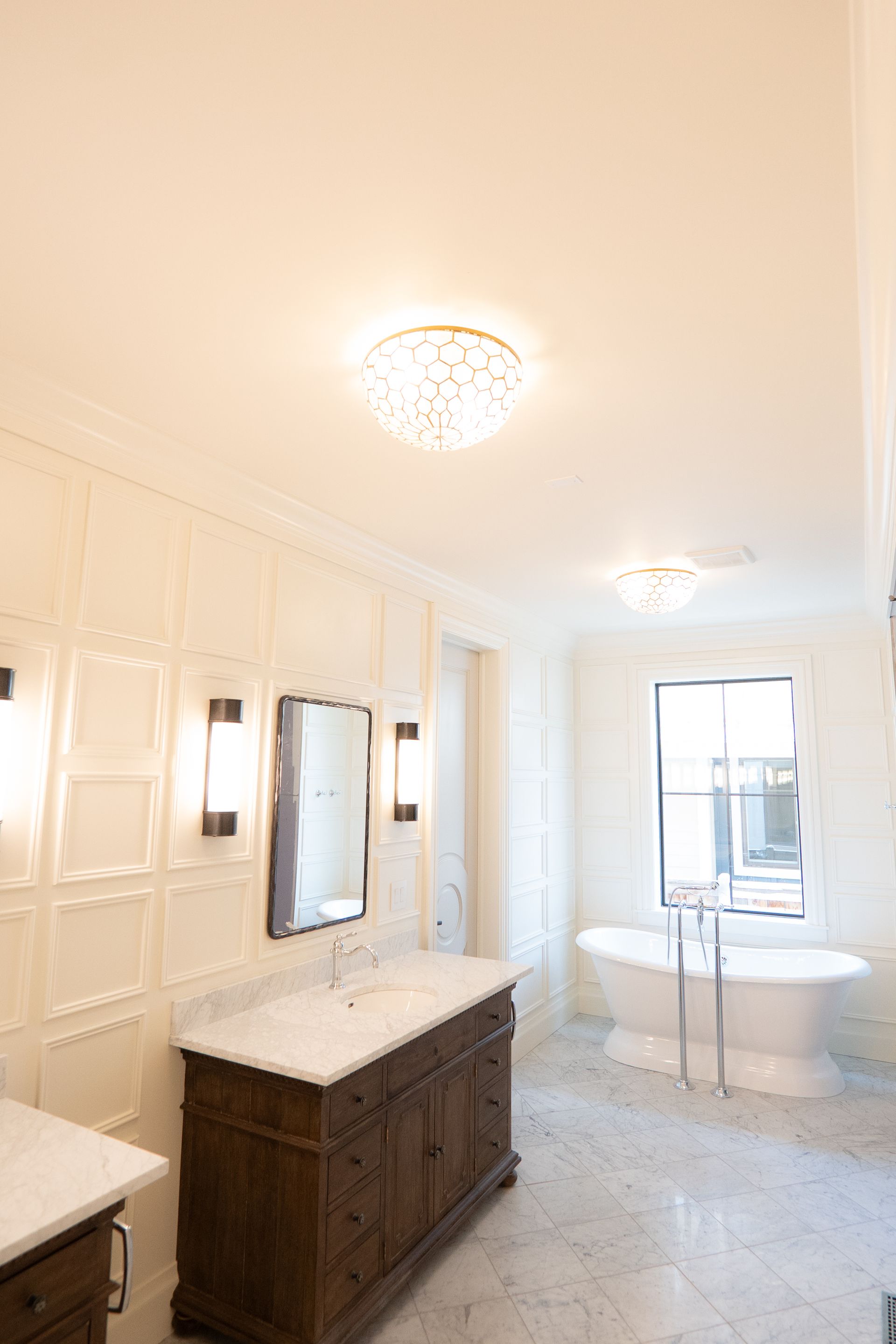 A bathroom with two sinks , a tub , a mirror and a window.