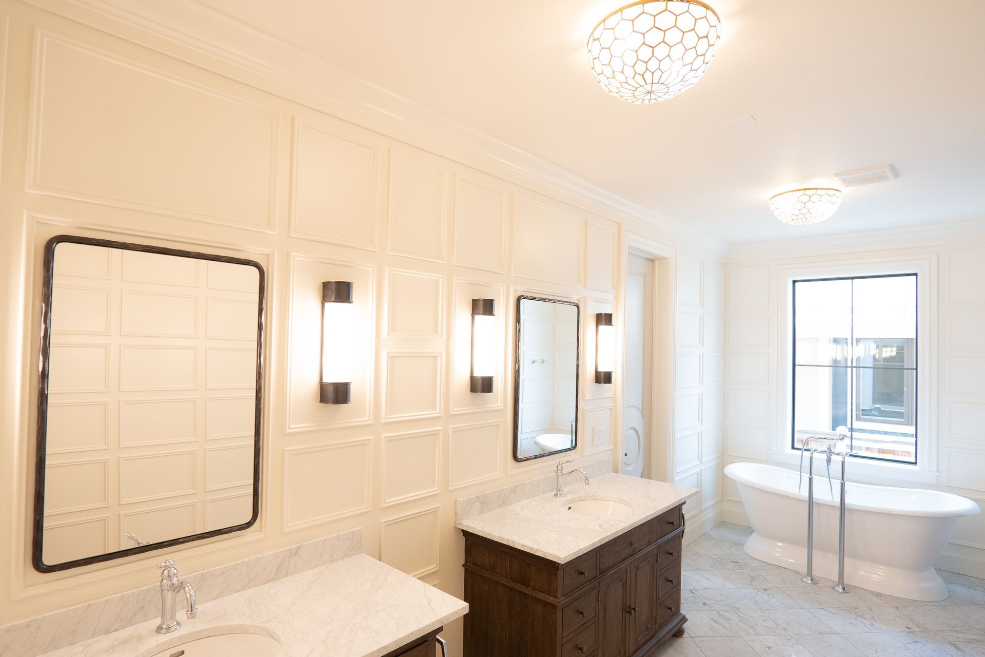 A bathroom with two sinks , two mirrors and a tub.