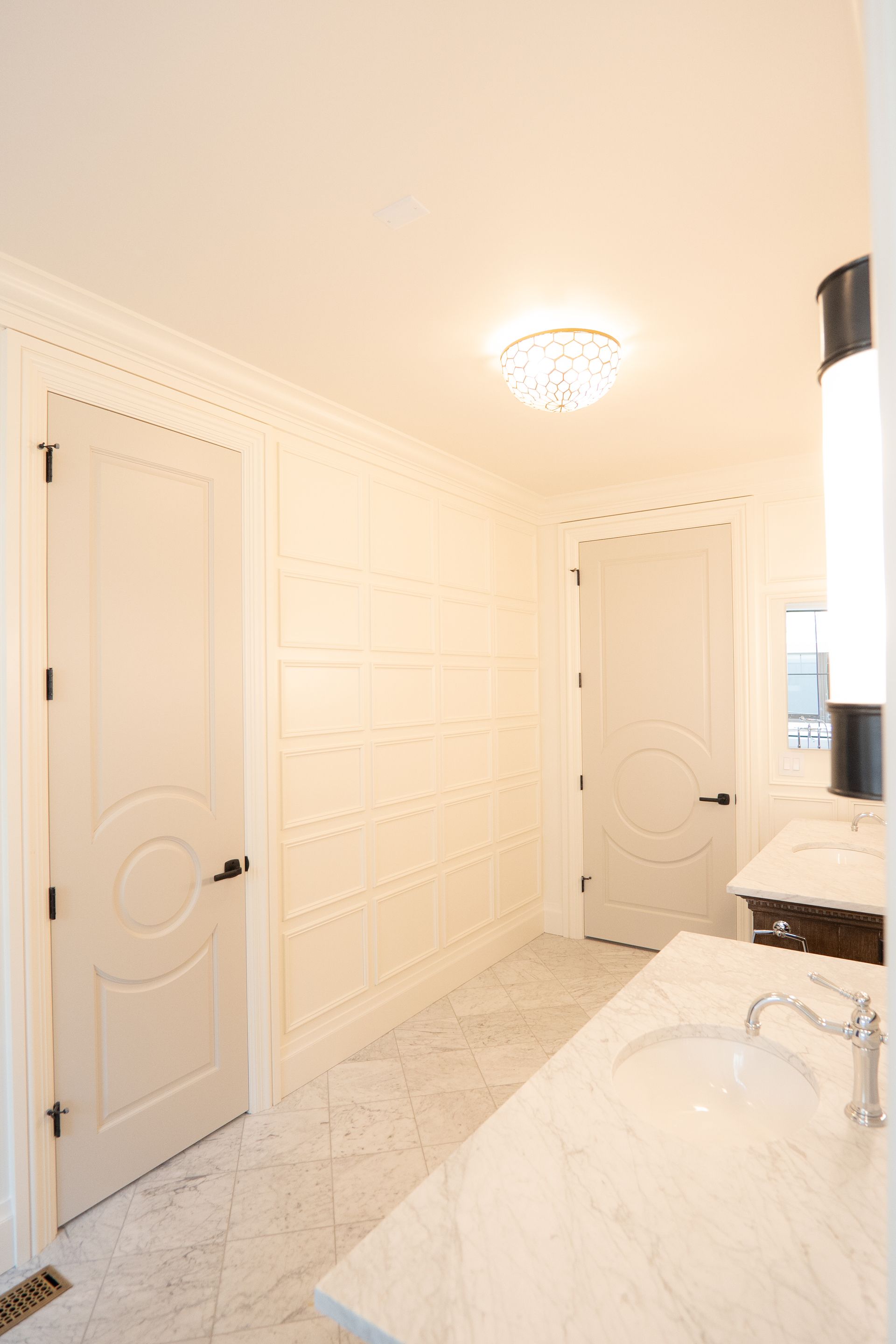 A bathroom with a sink , mirror and door.