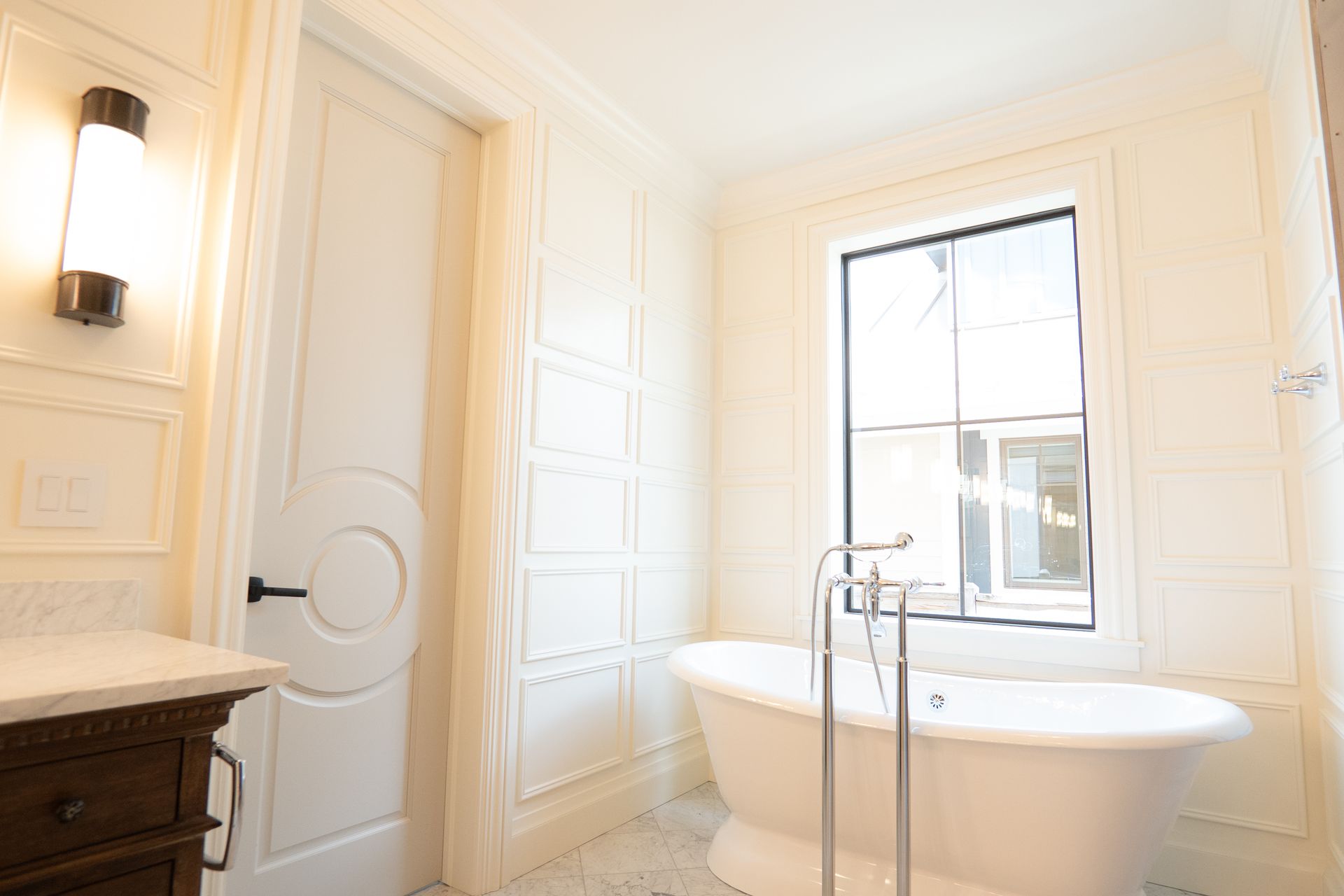 A bathroom with a tub , sink , and window.