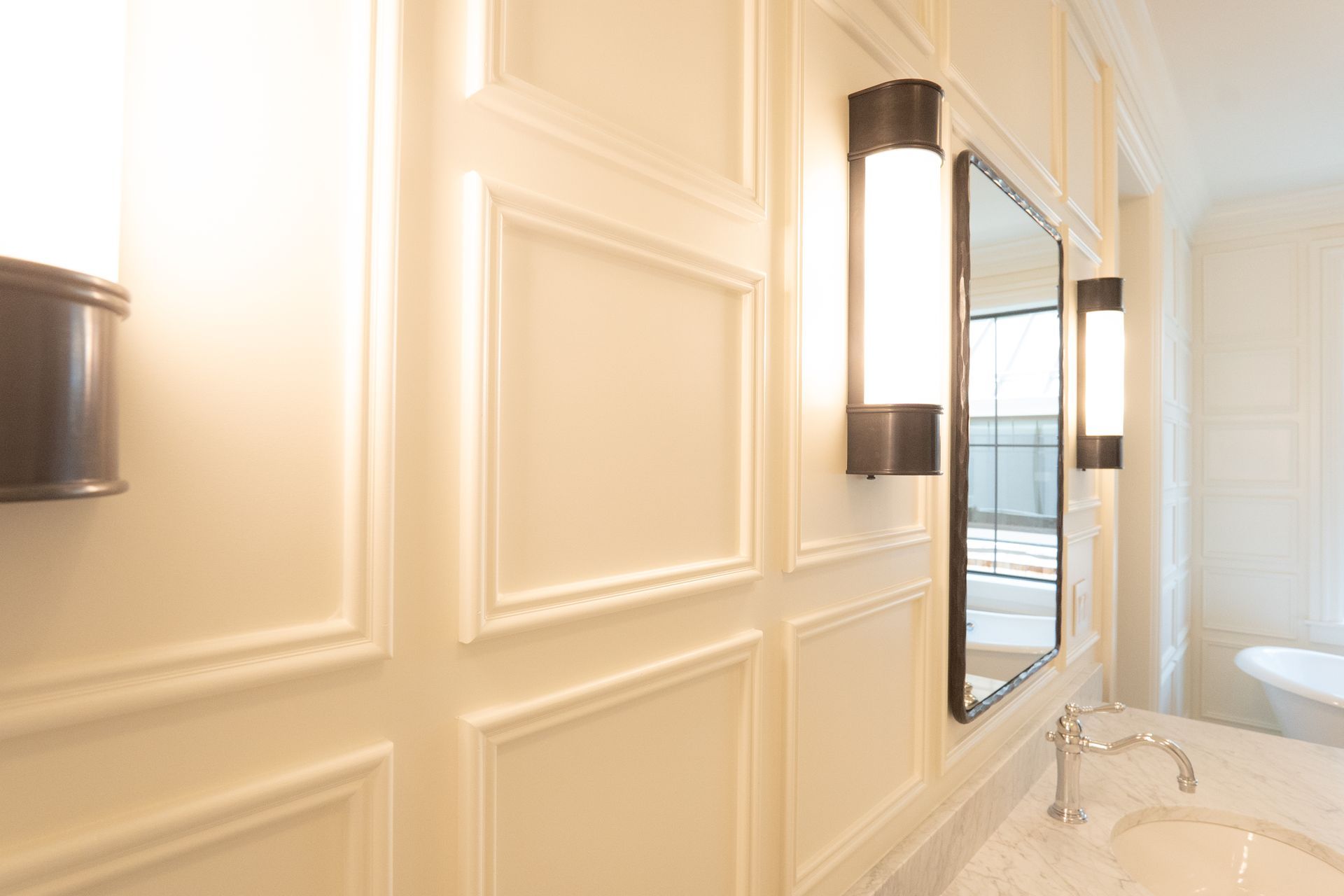 A bathroom with a sink , mirror and two lights on the wall.