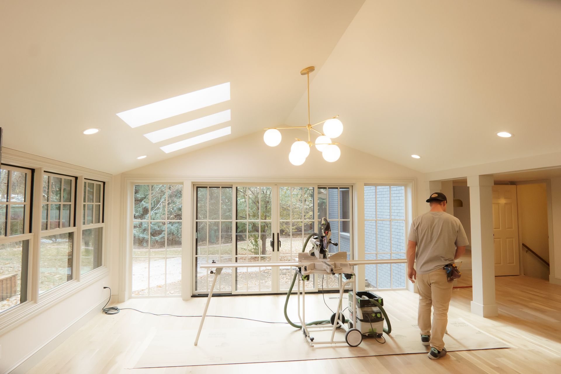 A man is walking through a large room with a lot of windows.