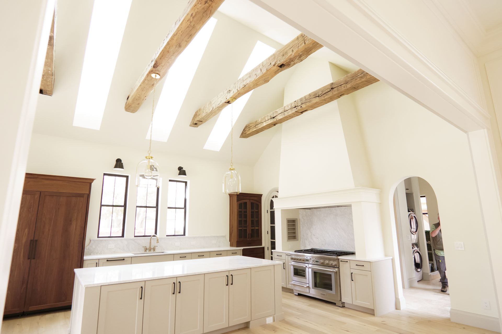 A kitchen with white cabinets and wooden beams on the ceiling.