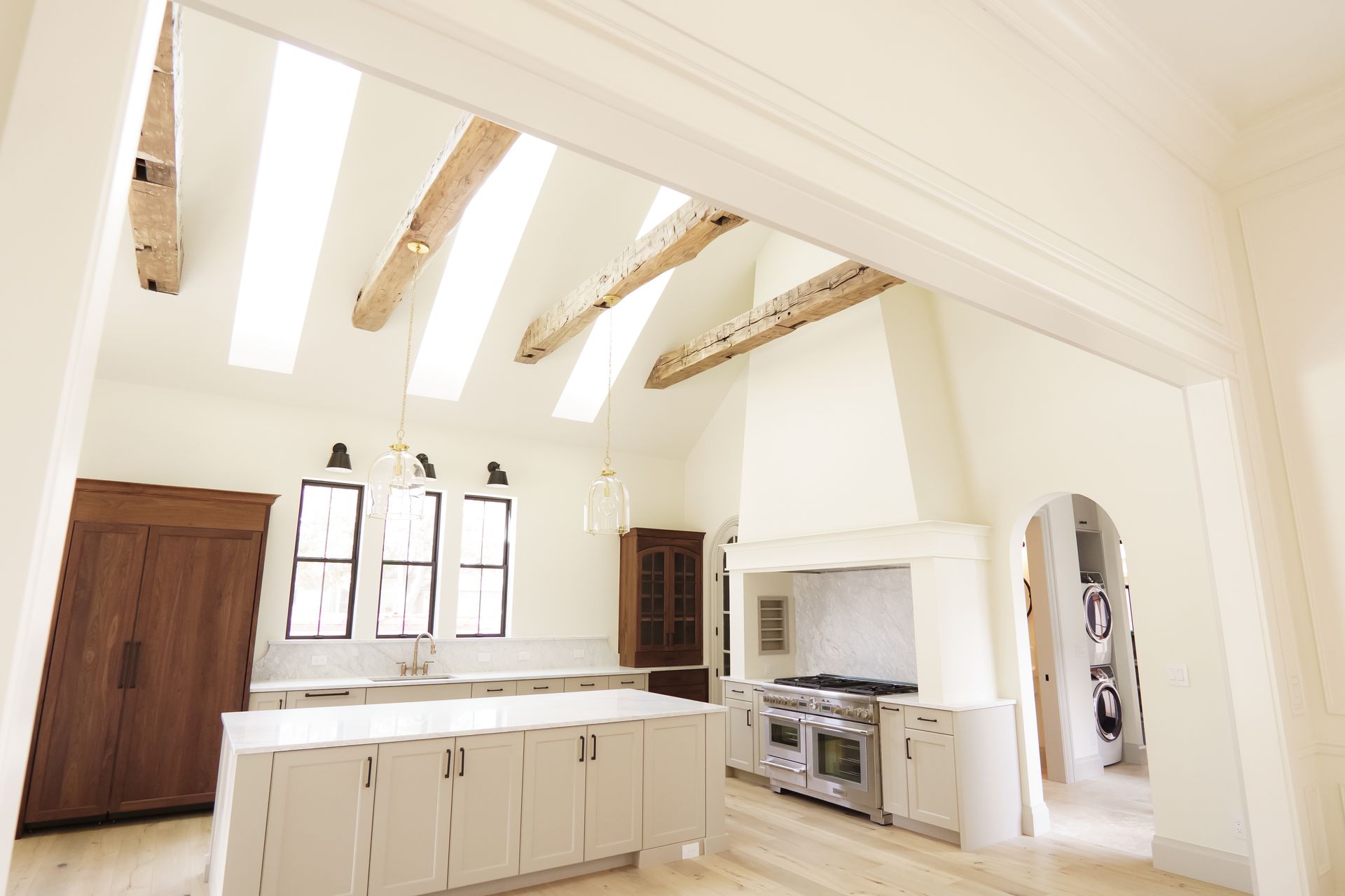 A kitchen with white cabinets and wooden beams on the ceiling