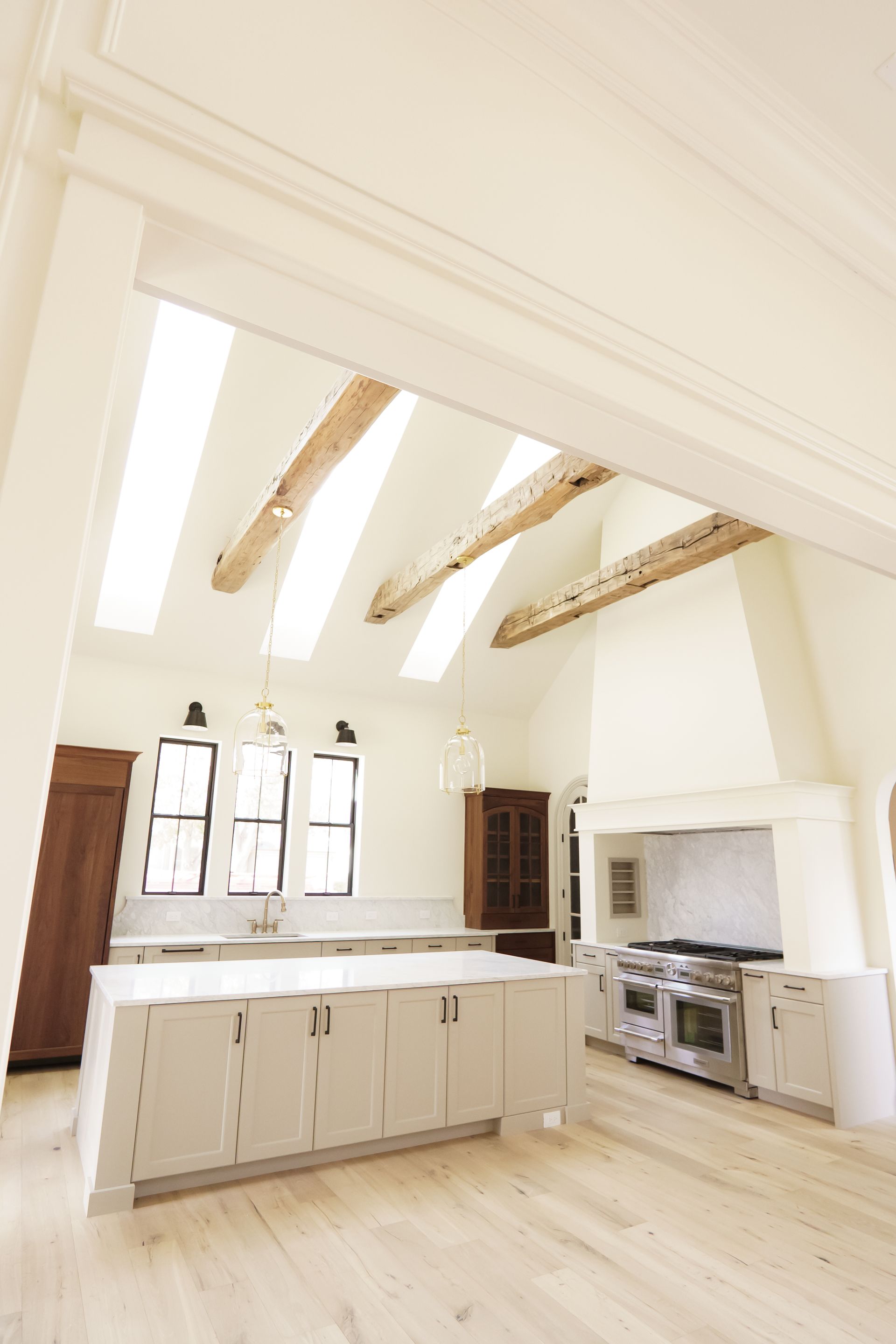 A kitchen with white cabinets and wooden beams on the ceiling.
