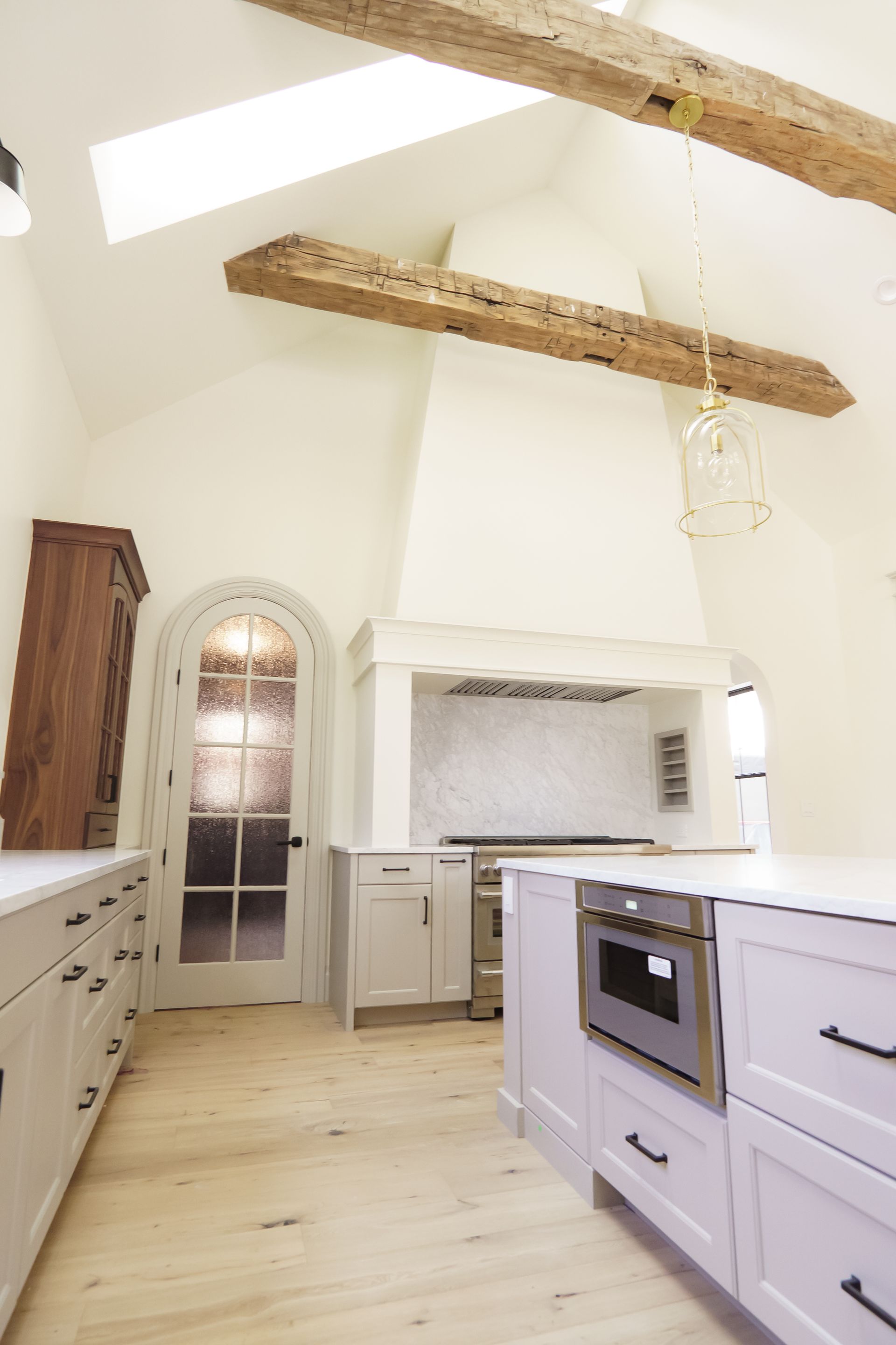A kitchen with white cabinets , stainless steel appliances , and wooden beams.