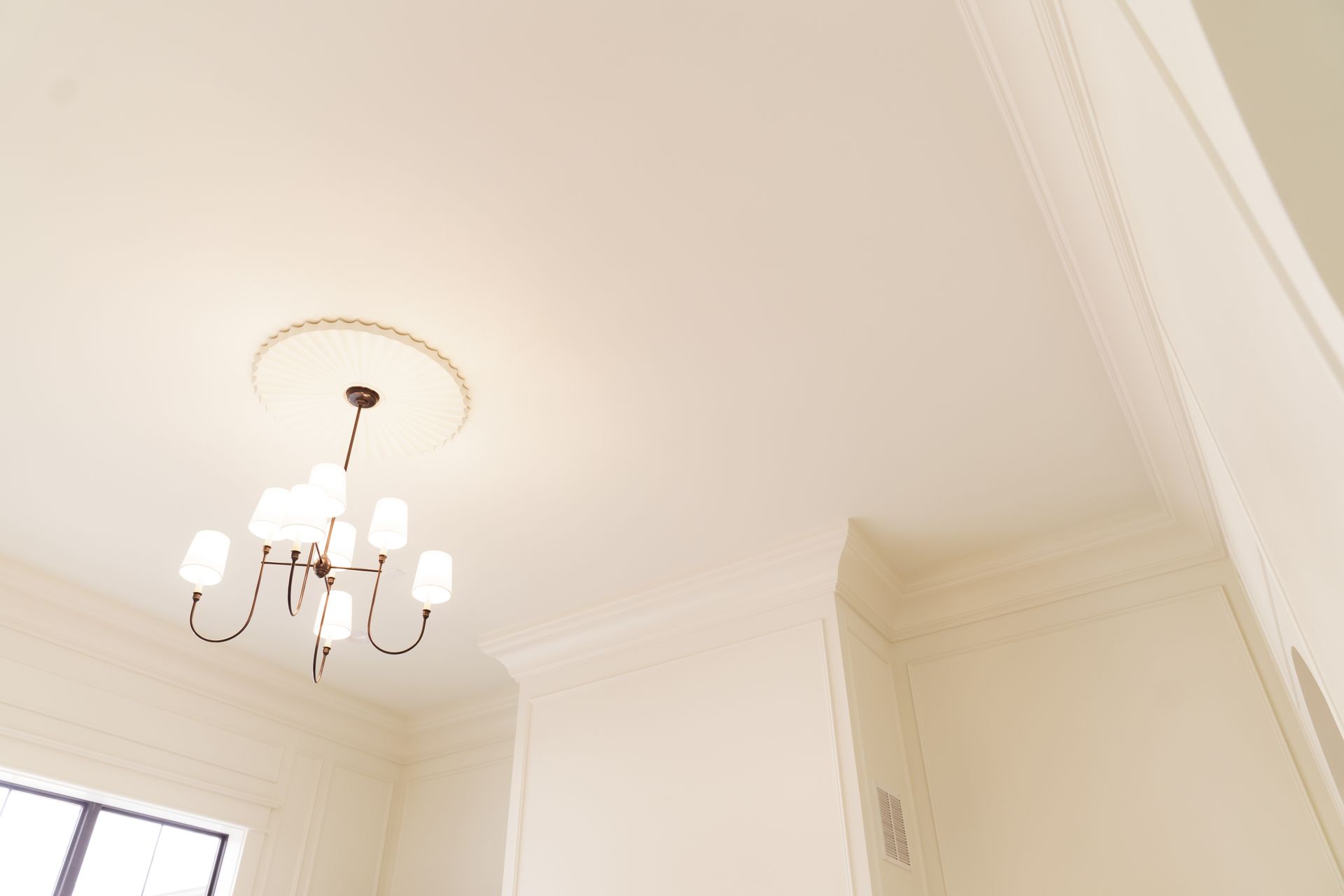 A white room with a chandelier hanging from the ceiling